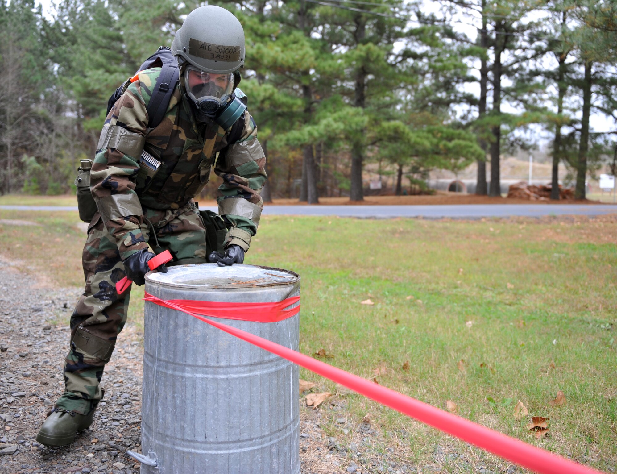 Airman 1st Class Brandon Shoop, 19th Force Support Squadron dining facility shift worker, uses tape to isolate an area around a simulated unexploded ordinance during a base exercise Nov. 18. (U.S. Air Force photo by Staff Sgt. Chris Willis)