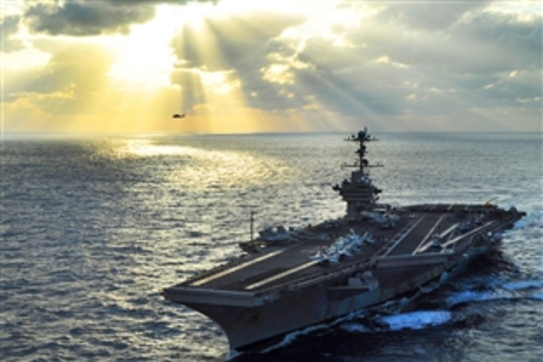 The aircraft carrier USS George Washington transits the Pacific Ocean while an SH-60B Sea Hawk helicopter assigned to Helicopter Anti-Submarine Squadron Light 51 conducts flight operations in the background, Nov. 18, 2009. The George Washington, the Navy's only permanently forward-deployed aircraft carrier, is underway supporting security and stability in the western Pacific Ocean.