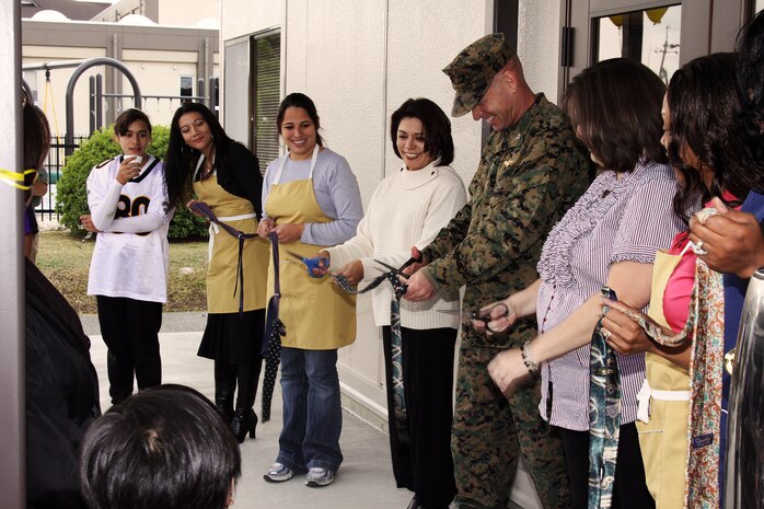 Marine Corps Air Station Iwakuni commanding officer, Col. Michael A. O’Halloran, flanked by Candice O’Halloran (left), Thift Store manager Gwen Peterson (right), and volunteers, directs a ribbon-cutting ceremony for the Thrift Store Saturday. Renovations and an expansion of the store began approximately two months ago and culminated in a grand opening ceremony over the weekend.