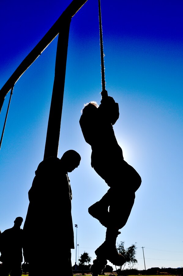 Jamey Guel, Marine Attack Squadron 311 dependent, climbs a rope after completing the obstacle course as her stepfather Cpl. David Guel, VMA-311 powerline mechanic, cheers her on at Ramada Field at the Marine Corps Air Station in Yuma, Ariz., during VMA-311’s Jane Wayne day Nov. 20, 2009. Jane Wayne days allow family members to experience the cornerstones of Marine training and conditioning, such as physical training and weapons handling. The family members got a taste of the Marine Corps Martial Arts Program, weapons training, obstacle course, combat fitness test and the station’s flight simulator during the squadron’s Jane Wayne day.