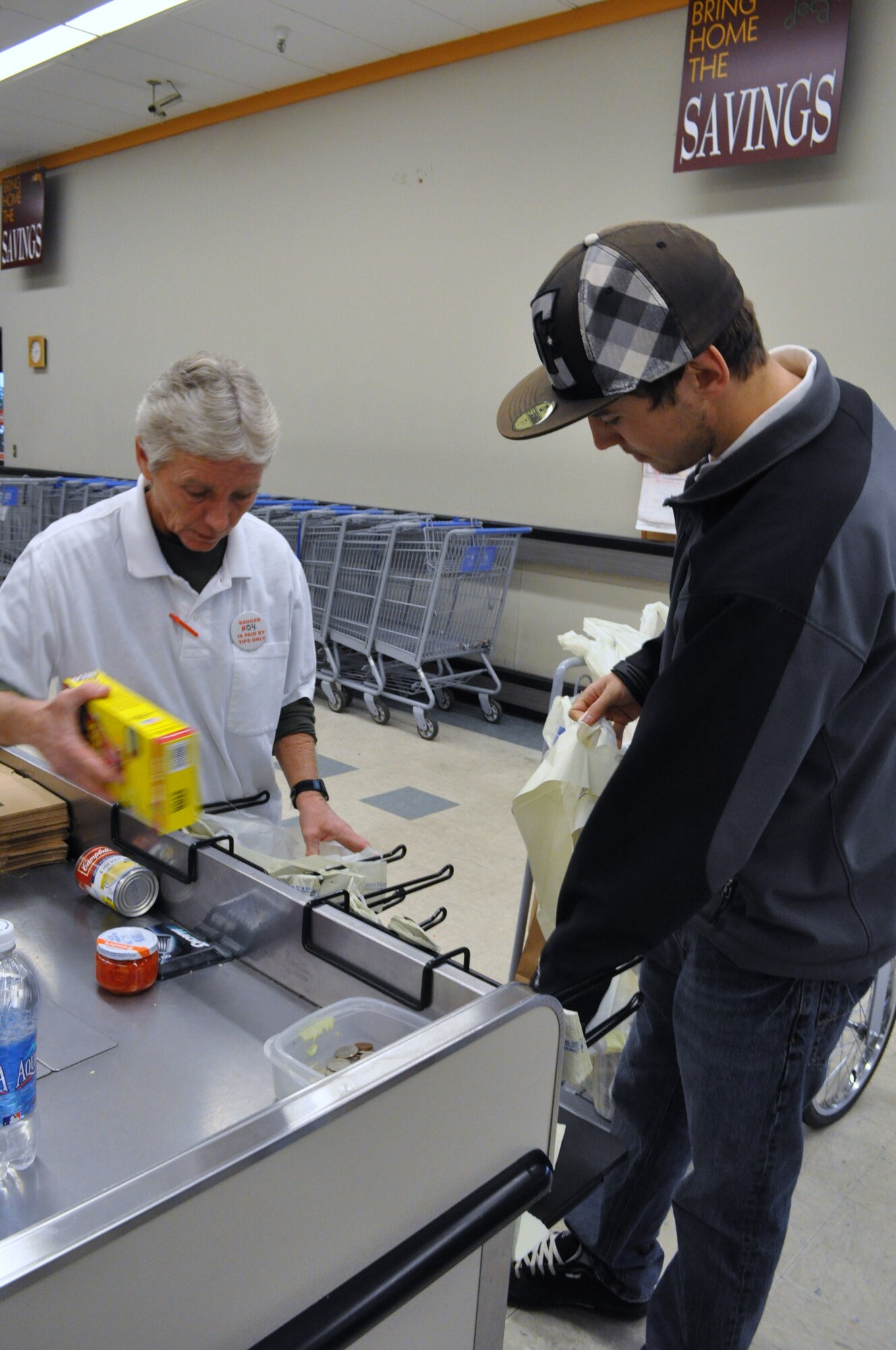 Commissary head bagger Bea Desmidt packs groceries with the help of assistant head bagger Zack Bailey.  Bailey and other assistant baggers Ryan Putnam, Dennis Oliver and Amanda Putnam aid Desmidt with keeping the bagger program running smoothly. They are a good point of contact for patron complaints with baggers and are usually working on the Express Lane.  (U.S. Air Force photo/Sonic Johnson)