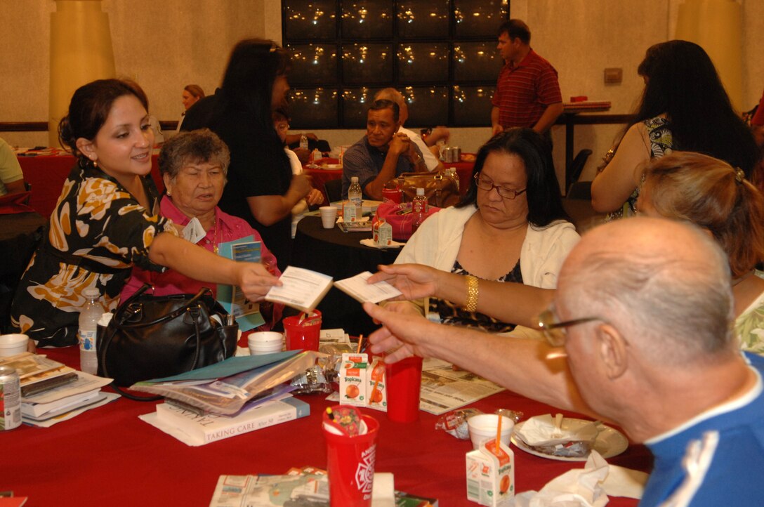 ANDERSEN AIR FORCE BASE, Guam - Belen Chambers, an office assistant for Army Air Force Exchange Services, hands out entry forms to retirees during the seventh annual Retiree Appreciation Day held here Nov. 21. Retirees who entered the drawing were eligible to win a home entertainment system feature a Blu-Ray player and a high-definition television. (U.S. Air Force photo by Senior Airman Shane Dunaway)