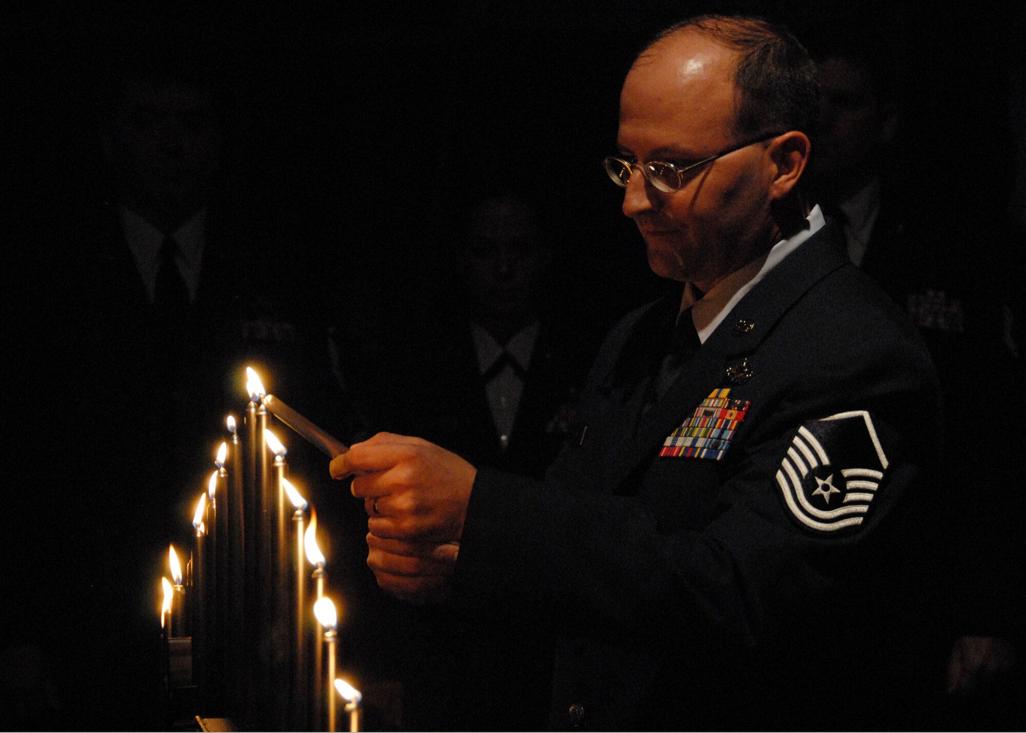 Master Sgt. Norman Houck, 919th Logistics Readiness Squadron, lights the final candle during the senior NCO induction ceremony at Duke Field Nov. 7.  The ceremony was held to honor new staff sergeants and master sergeants within the wing.    (Air Force photo/Staff Sgt. Samuel King Jr.)