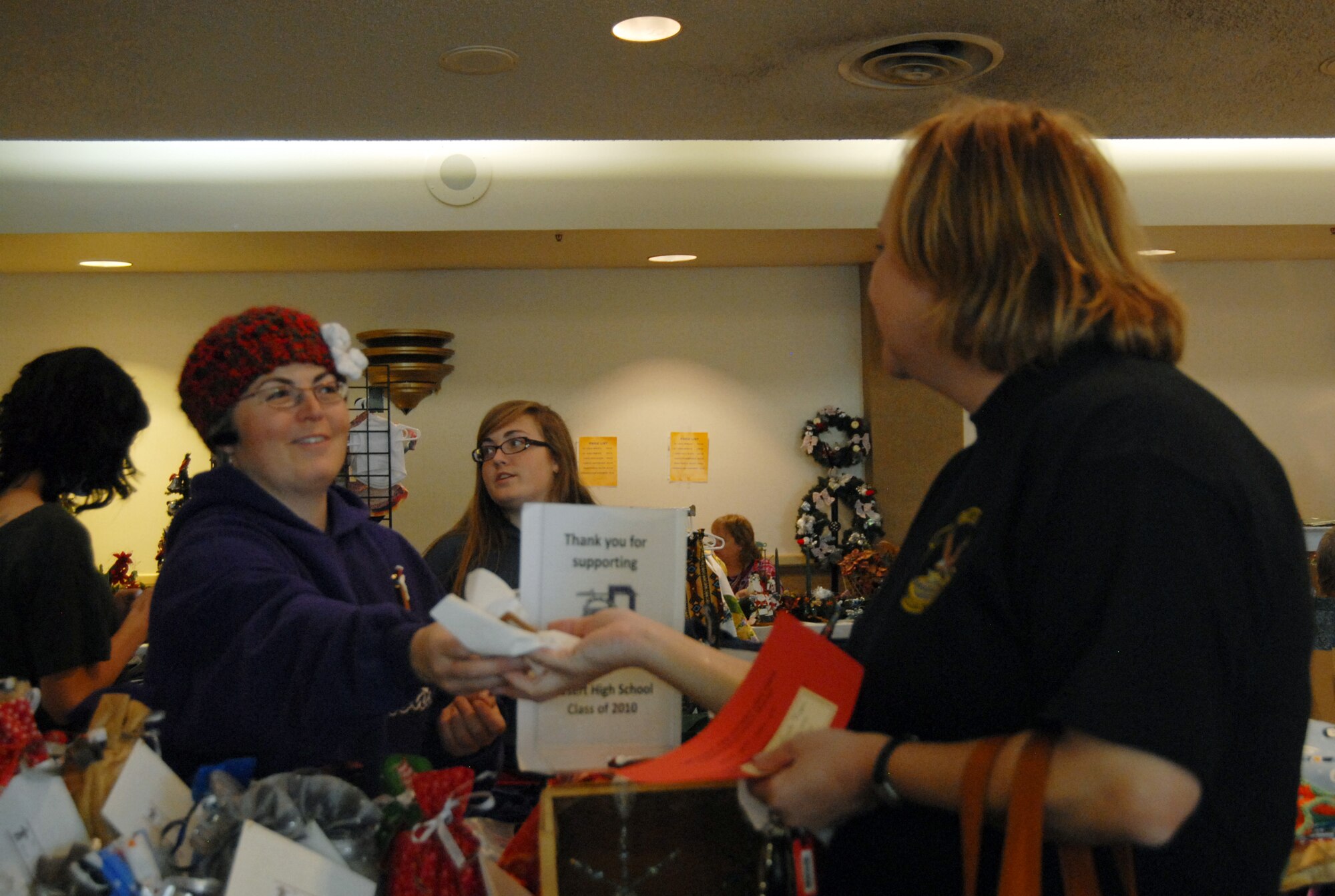 Lisa Corbin (left), a vendor, gives out samples at the Desert High senior class fundraiser booth during the Mistletoe Bazaar at Club Muroc Nov. 20. The Edwards Enlisted Spouses Club hosts the Mistletoe Bazaar annually to support Edwards community programs. (Air Force photo/2nd Lt. Belena Marquez)