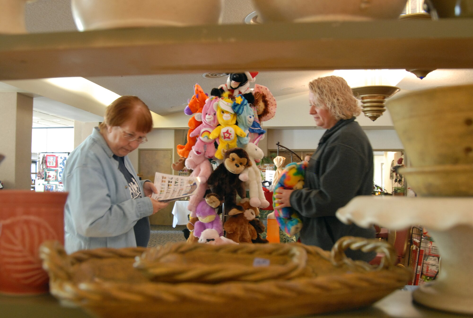 Sarah Nolet (right),a vendor, shows merchandise to a customer Nov. 20 during the Mistletoe Bazaar at Club Muroc. The Edwards Enlisted Spouses Club hosts the Mistletoe Bazaar annually to support community programs. (Air Force photo/2nd Lt. Belena Marquez)