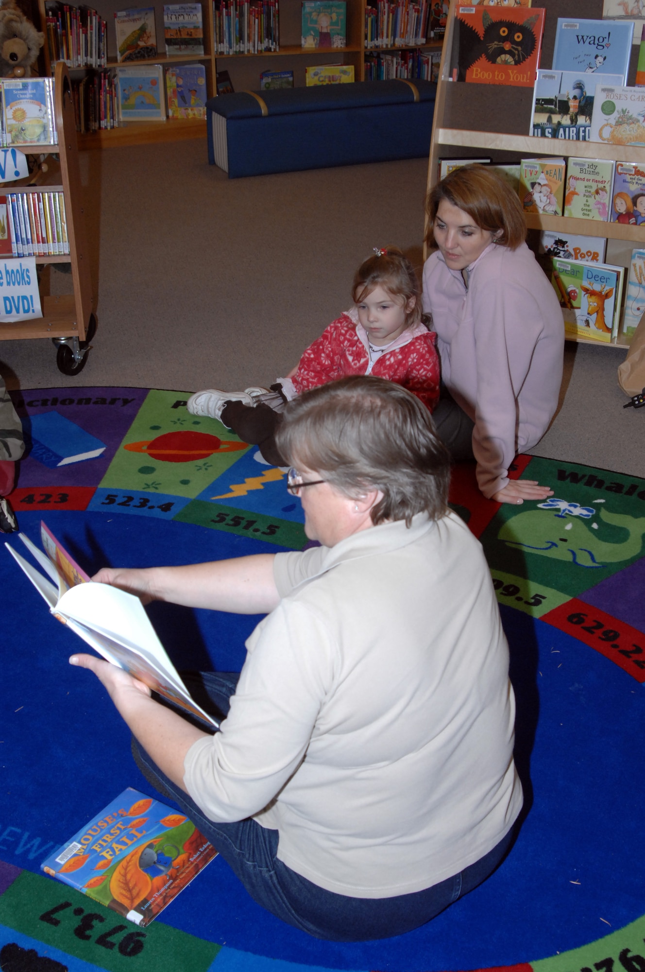 Senior library technician Velvet Marlin, 62nd FSS, reads a book to Cecilia Williams, accompanied by her mother, Jodi Williams, during Preschool Storytime at the McChord library Nov. 19. Preschool Storytime is held 11 a.m. and 3 p.m. each Thursday at the library, and features stories, songs, crafts and more. The activities are just one way the base supports the Team McChord community and Year of the Air Force Family. (U.S. Air Force photo/Randy White)