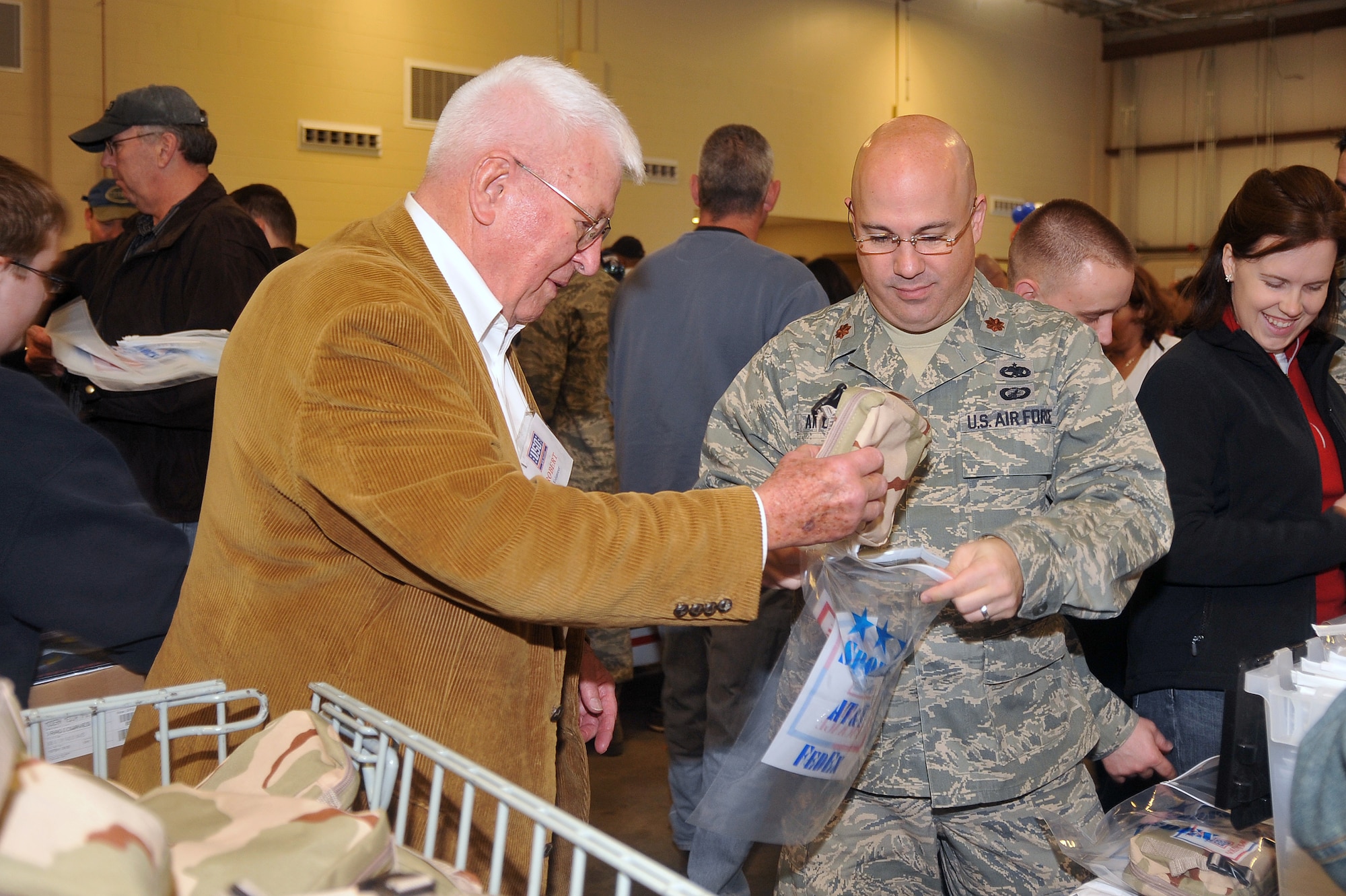 HANSCOM AIR FORCE BASE, Mass. - Maj. Gen. (Ret.) Robert Davenport, a World War II veteran, and Maj. John Amodeo, 631st Electronic Systems Squadron, volunteer on the troop care package assembly line together Nov. 21 at the Operation United Service Organizations Care Package event, where two shifts of 200 volunteers including military, family members, Boston Celtics Dancers, USO representatives and many others packed 10,000 boxes of snacks, toiletries, books and other supplies here at Hanscom. (U.S. Air Force Photo by Mark Herlihy)