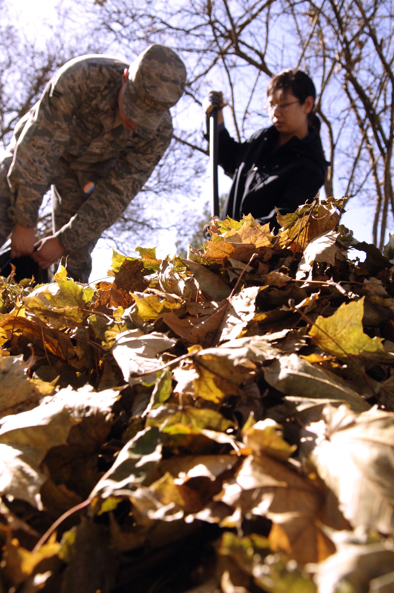 FAIRCHILD AIR FORCE BASE, Wash. - Airman 1st Class Jianna Goto, 92nd Logistic Readiness Squadron, and Airman 1st Class Colton Papke, 92nd Aircraft Maintenance  Squadron, work together to rake a pile of leaves from the yard of a deployed Airman’s home here Nov. 7.  Airman Goto and Airmen Papke were two of the many Airmen who volunteered to help rake approximately 15 homes for spouses of deployed Airmen through the Airman’s Ministry Center.  (U.S. Air Force Photo/ Airman 1st Class Natasha E. Stannard)