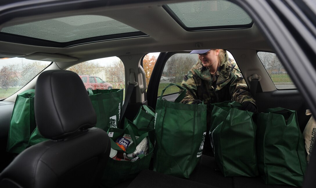 LANGLEY AIR FORCE BASE, Va. - After filling bags with Thanksgiving food during Operation Warmheart Nov. 23, Tech. Sgt. Michelle Grover, 192nd Fighter Wing Weapon Systems controller, loads the bags into a vehicle for distribution.  Operation Warmheart is a First Sergeants' Association community outreach program designed to support Airmen and their families during the holiday season. (U.S. Air Force photo/Senior Airman Zachary Wolf)