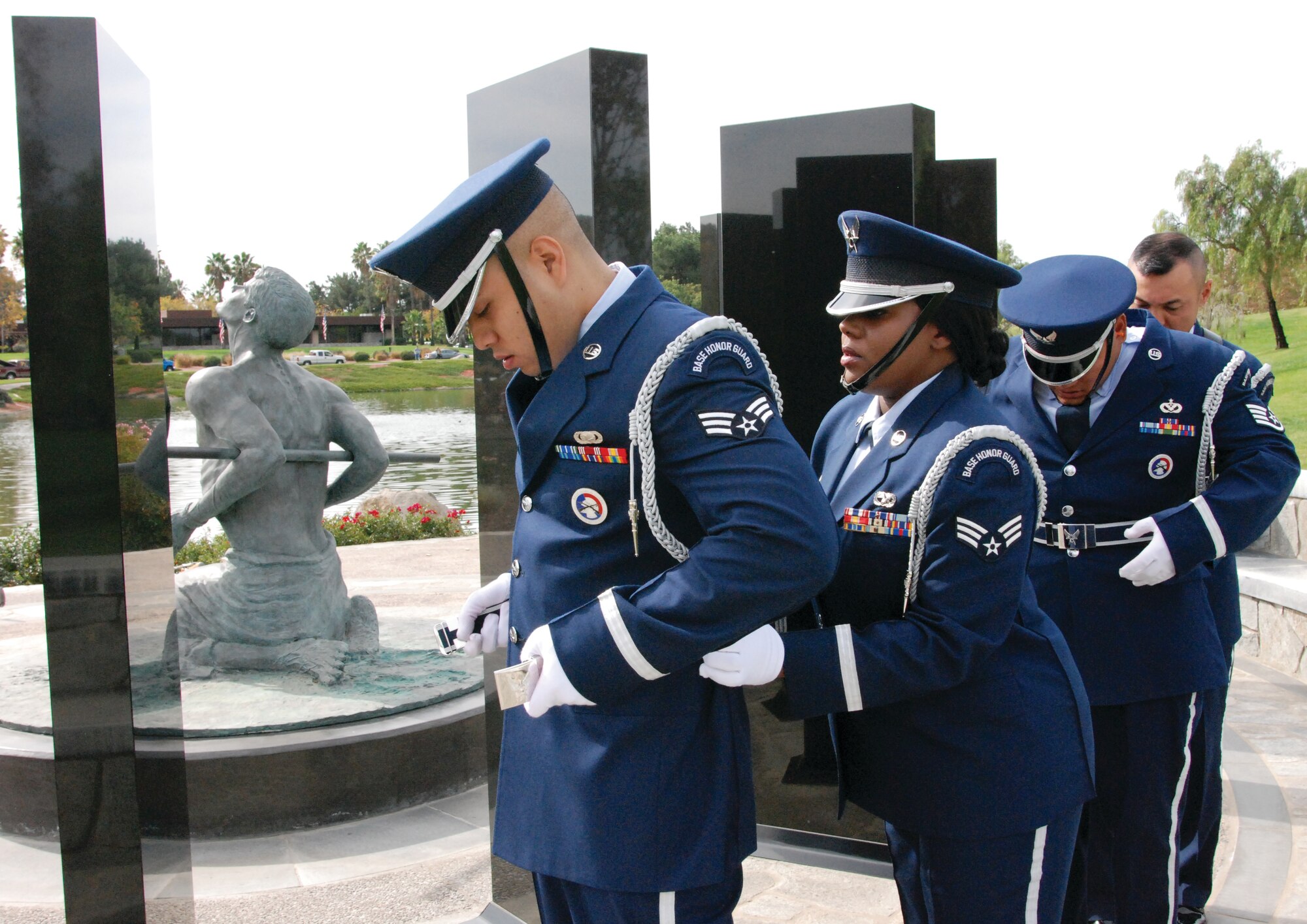 Behind the POW/MIA Memorial, Senior Airman Valysia Reed assists Senior Airman Oscar Coreas with his belt as they transition from rifle honors to retiring the colors in the Daedalians’ Veterans Day Memorial Service at Riverside National Cemetery Nov. 11.(U.S. Air Force photos by Megan Just)