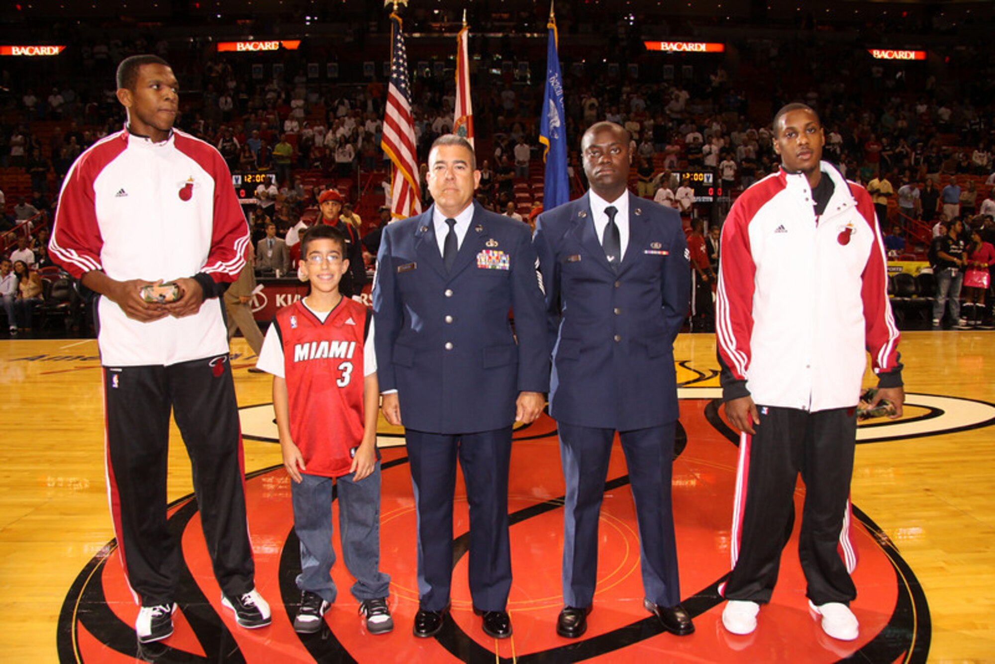 Senior Master Sgt. Antonio Romero (left) and Senior Airman James Jean (right), 93rd Fighter Squadron members, were recognized during the pre-game ceremony of the Miami Heat vs. New Orleans Hornets game as part of the team's “Home Strong” Program on Nov. 22.The program, championed by NBA Hall of Famer and Heat President Pat Riley, recognizes military members who served in Iraq or Afghanistan and praises the contributions of military families during each home game.During the ceremony, the Airmen were presented with Miami Heat championship customized dog tags by forward James Jones and guard Mario Chalmers. (Photo courtesy of the Miami Heat)