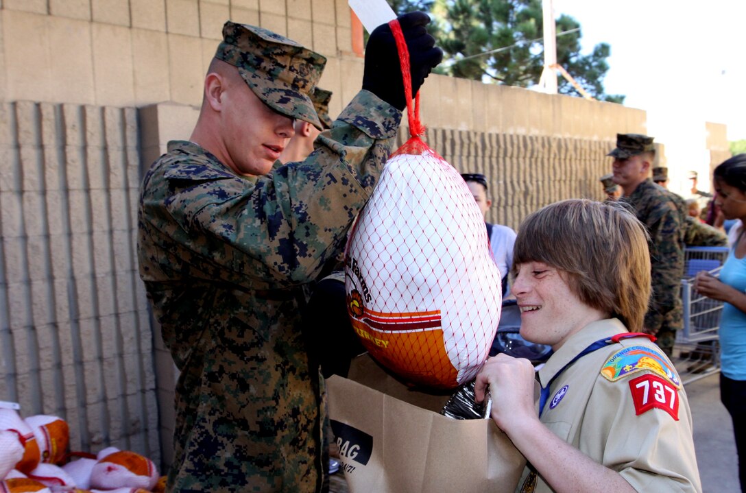 Pvt. Adam Johnson, student, School of Infantry, places a turkey into Boy Scout Eric Blackburn’s grocery bag during the 7th annual Thanksgiving turkey giveaway hosted by the San Clemente Military Family Outreach at Camp Pendleton, Nov. 23. More than 300 service members and family came out to receive free turkeys and other food items such as pies and canned goods. Patrons also received recipe books and cooking materials. The donations, gathered from San Diego County churches, business and individuals, were passed out by Marines from SOI and children from local youth organizations.::r::::n::