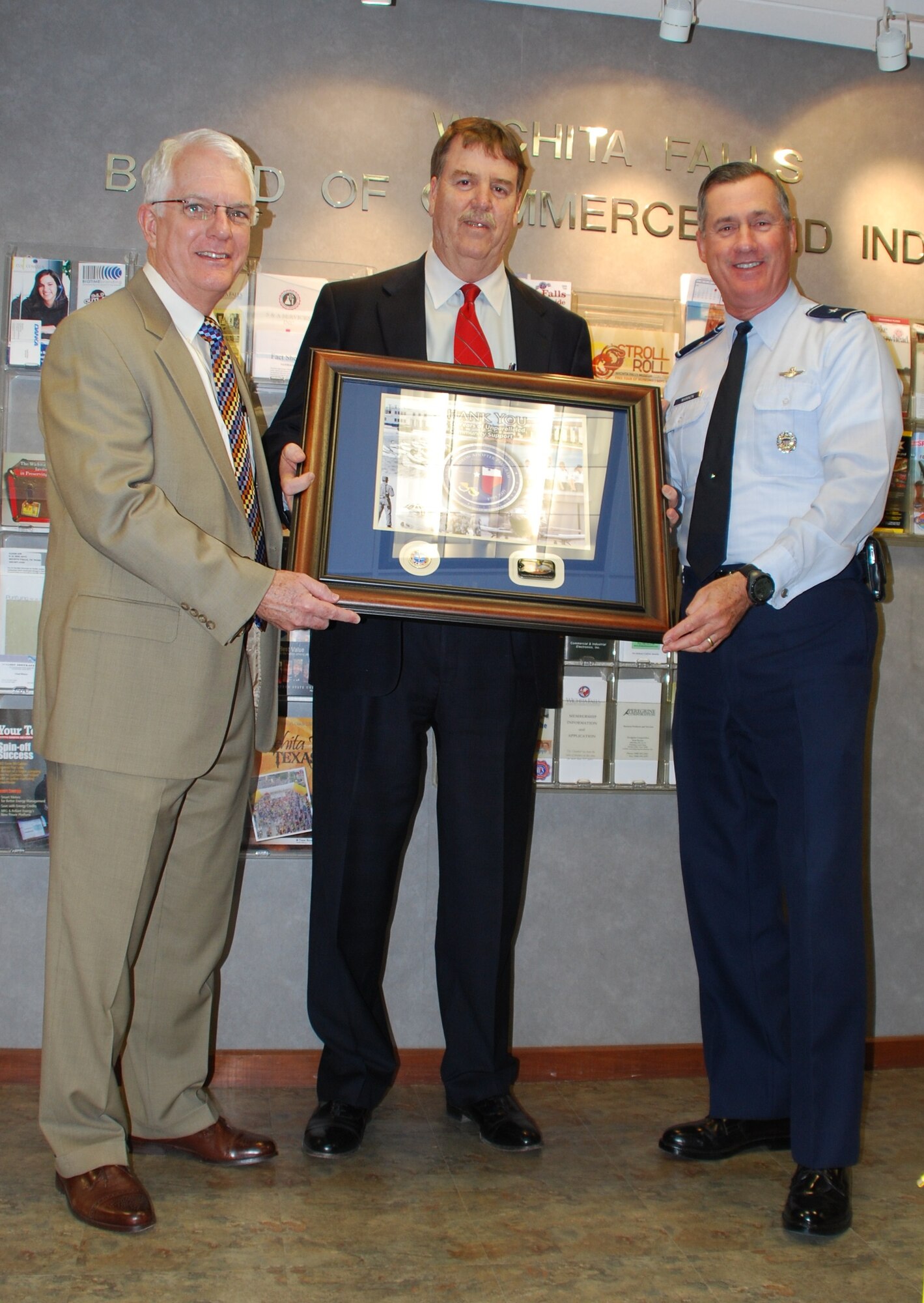 Tom Whaylen, Military Affairs Committee President, and Darrell Coleman, Times Record News President, pose during a Squadron Adopter plaque presentation with Brig. Gen. O.G. Mannon, 82nd Training Wing at the Chamber of Commerce office in Wichita Falls, Texas. The Adopter Program celebrates its 50th anniversary this year. (U.S. Air Force photo/Airman 1st Class Valerie Hosea)  