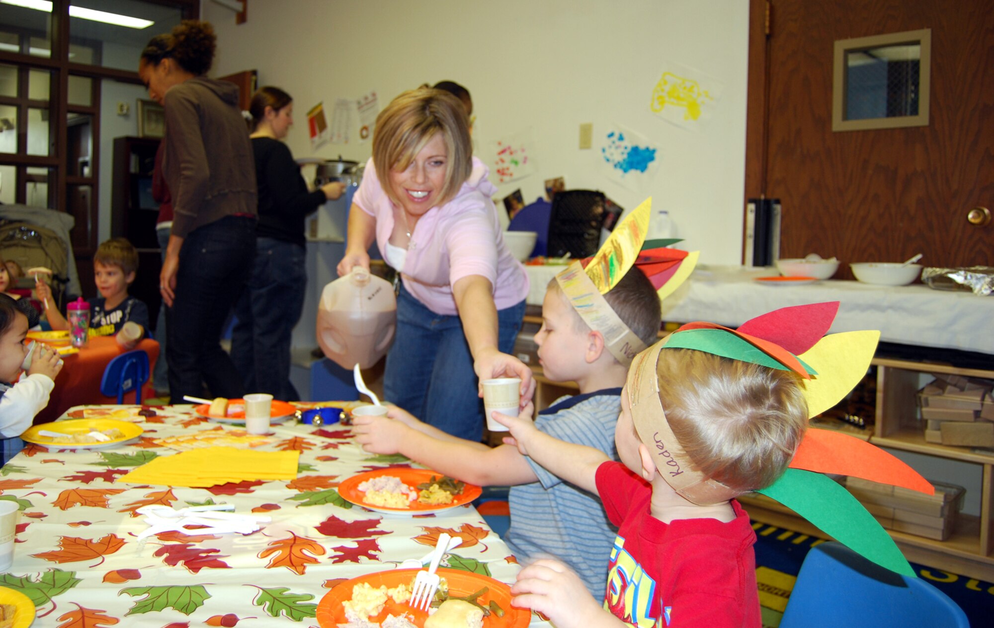 Family Child Care Provider Jolee Pace hands 2-year-old Kayden a class of chocolate milk while 4-year-old brother Nicholas gets ready to put his cup down. More than 50 child care providers, parents and children gathered for a Thankful Feast Nov. 20 to celebrate all the things they are thankful for. Families brought their favorite dish along to share. (U.S. Air Force photo/Tech. Sgt. Marcus McDonald)