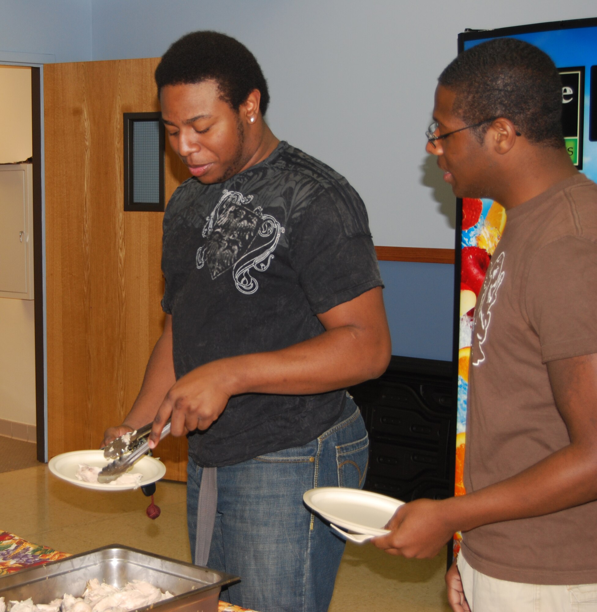 Tristan Fields and Senior Airman Freeman Davis, 341st Missile Security Forces Squadron member, make plates of turkey, chicken and mashed potatoes and gravy at the annual community Thanksgiving dinner at the Chapel Annex Nov. 22, 2009. Members of the Catholic and Protestant communities provided the side dishes and desserts. The chapel supplied the meat, potatoes and rolls. (U.S. Air Force photo/Airman 1st Class Kristina Overton)