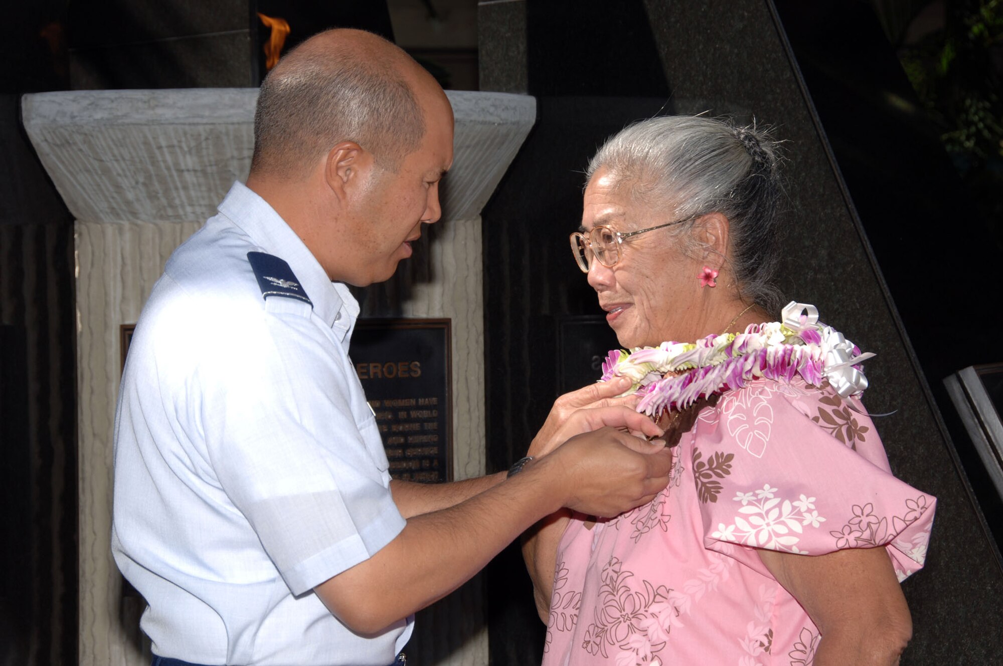 HICKAM AIR FORCE BASE, Hawaii – Col. Giovanni Tuck, 15th Airlift Wing commander, attaches a commemorative pin to the lapel of Carol Kawai, 15th Operations Group secretary, honoring her 50 years of Federal service. The ceremony in the Courtyard of Heroes here Nov. 23 recounted Ms. Carol’s legacy of service to the U.S. Air Force, which she took “two years at a time” once she was eligible to retire (25 years ago). (U.S. Air Force photo by Vanessa Forloine)
