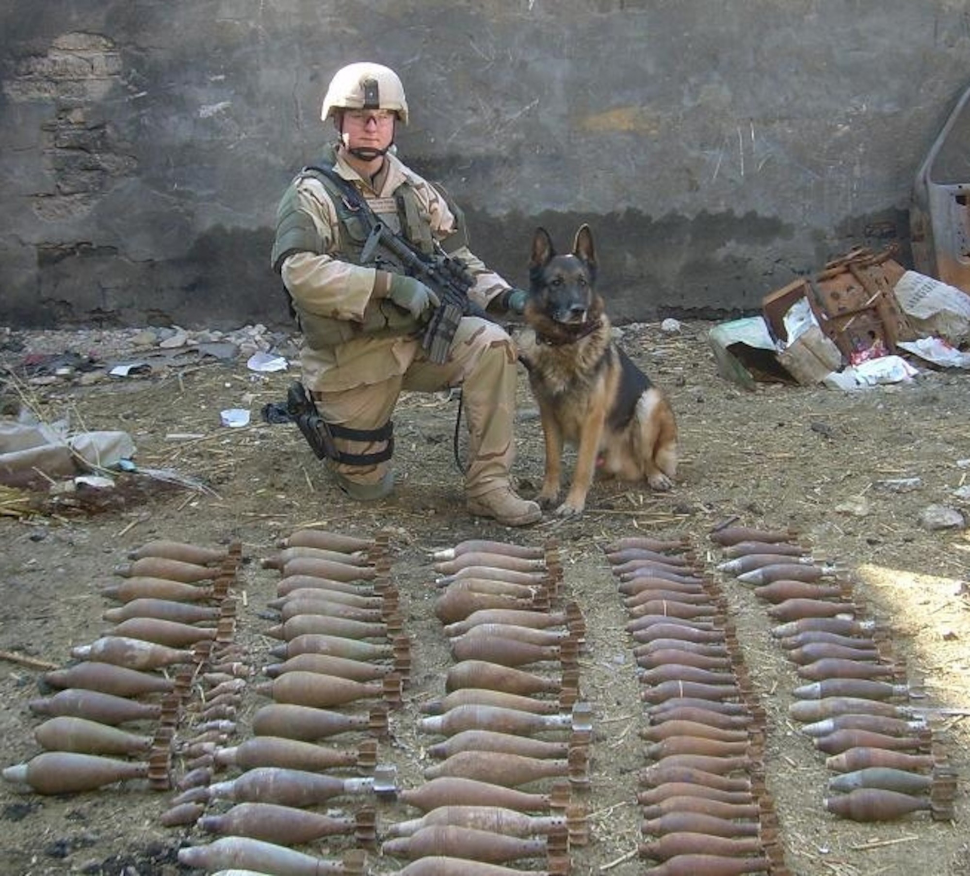 ELMENDORF AIR FORCE BASE, Alaska -- Military working dog and his handler pose for a photo in front of explosives found during a deployment. MWD Benjo retired Nov. 12, 2009.(U.S. Air Force photo)        