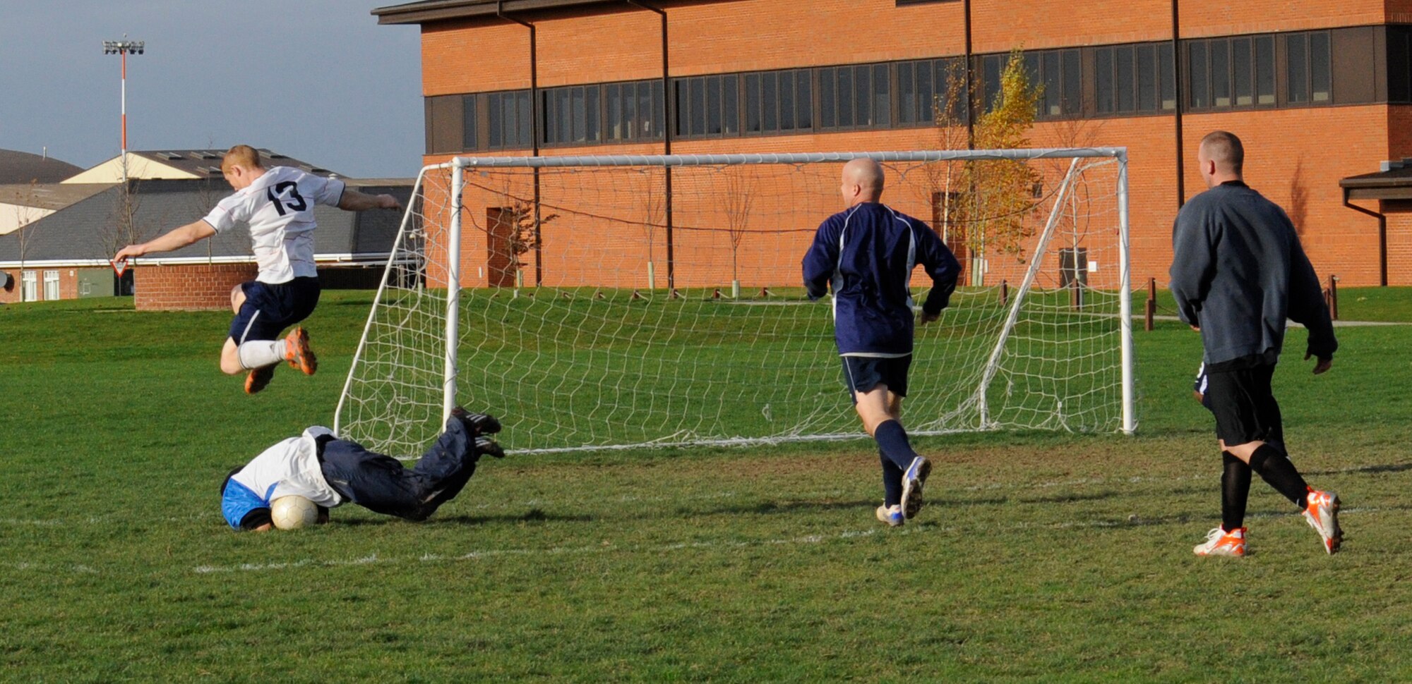 Sean Behringer, 100th Logistics Readiness Squadron player, jumps to avoid clashing with  Paul Cavanes, 488th Intelligence Squadron/95th Reconnaissance Squadron goalie, in the intramural soccer championship match at the Hardstand Fitness Center Nov. 19. Behringer scored the first goal with a sweet left foot shot that went in off the post to send LRS on their way. (U.S. Air Force photo/Staff Sgt. Christopher L. Ingersoll)