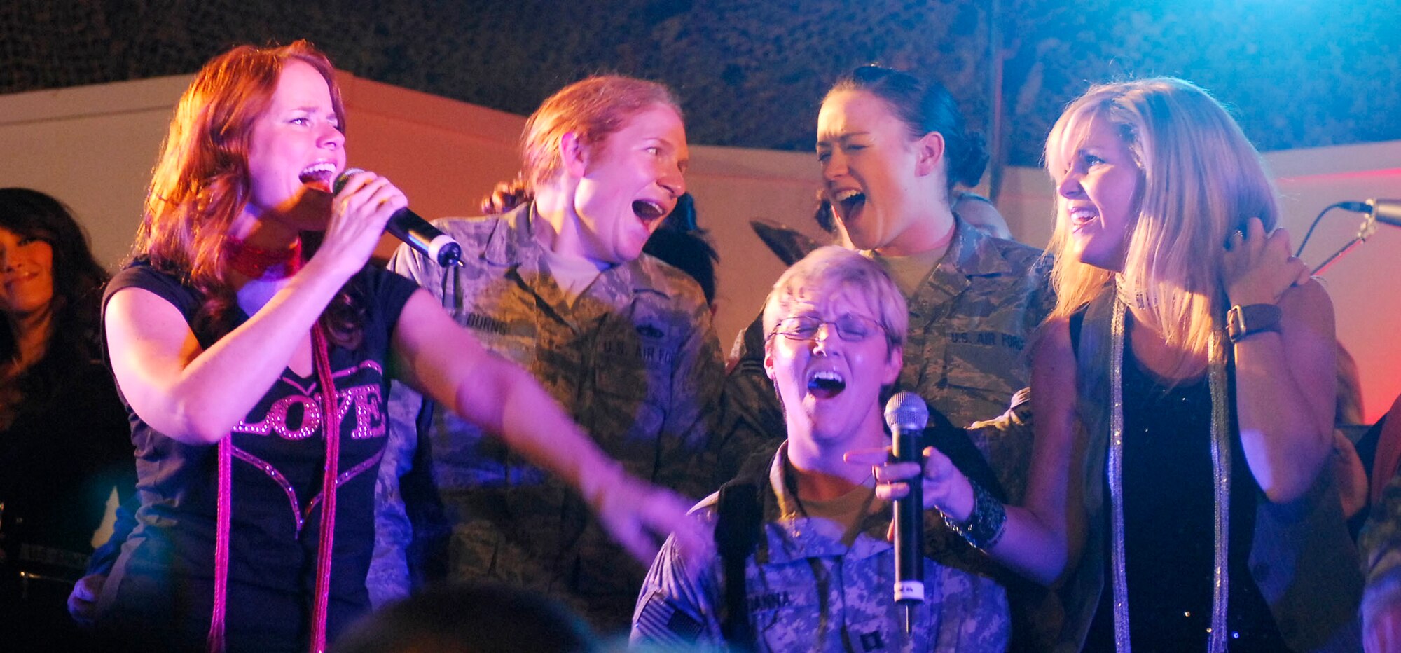 Tech. Sgt. Amanda Burns (left) and Senior Airman Kayla Bilger (right) sing onstage with members of the Lieutenant Dan Band Nov. 23, 2009, at Bagram Airfield, Afghanistan. Sergeant Burns, a Falmouth, Ken., native deployed from the U.S. Air Force Academy, won a pair of round trip tickets to anywhere in the states. Airman Bilger is from Hartland, Mich., and is deployed from Geilenkirchen Air Base Squadron, Germany. (U.S. Air Force photo/Senior Airman Susan Tracy)
