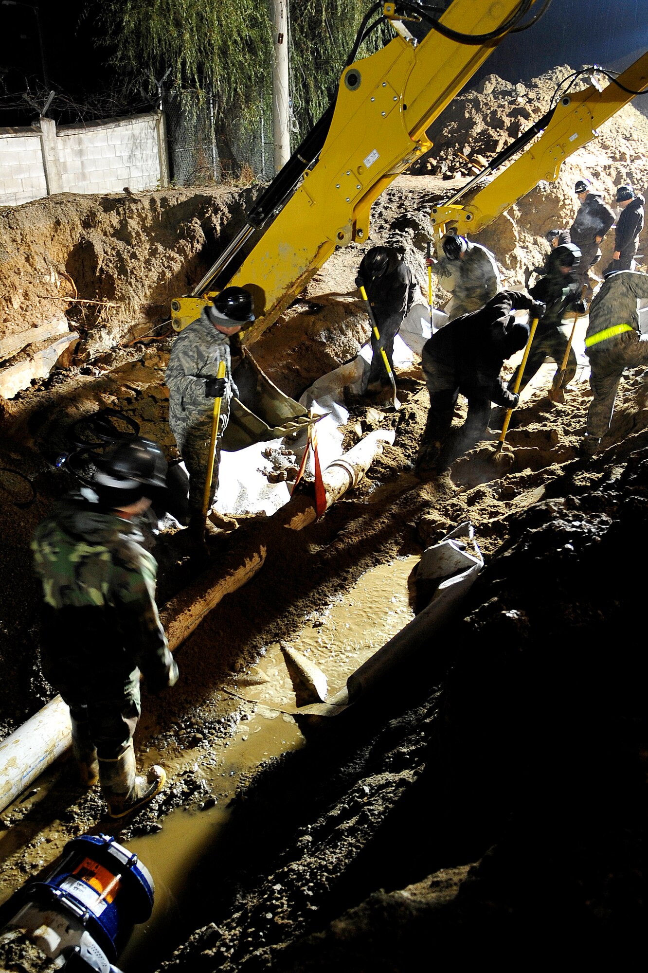 Airmen from the 51st Civil Engineer Squadron use shovels to cover the newly replaced section of eight-inch water main that ruptured at Osan Air Base, Republic of Korea, Nov. 20. The pipe broke due to an underground slippage of concrete that was used to cover a pre-existing benjo ditch near the pipes. Airmen and civilians from agencies across Osan worked together for more than 24 hours repairing the broken eight and 12 inch water mains. (U.S. Air Force photo/Staff Sgt. Brian Ferguson)
