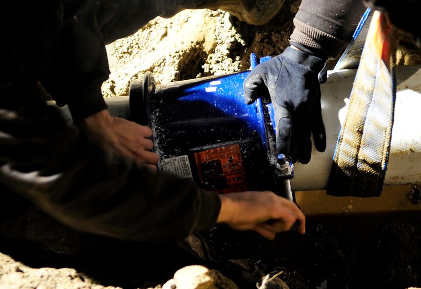 Airmen from the 51st Civil Engineer Squadron tighten a pipe connector as they replace a section of an eight-inch water main that ruptured at Osan Air Base, Republic of Korea, Nov. 20. The pipe broke due to an underground slippage of concrete that was used to cover a pre-existing benjo ditch near the pipes. Airmen and civilians from agencies across Osan worked together for more than 24 hours to repair the broken eight and 12 inch water mains. (U.S. Air Force photo/Staff Sgt. Brian Ferguson)