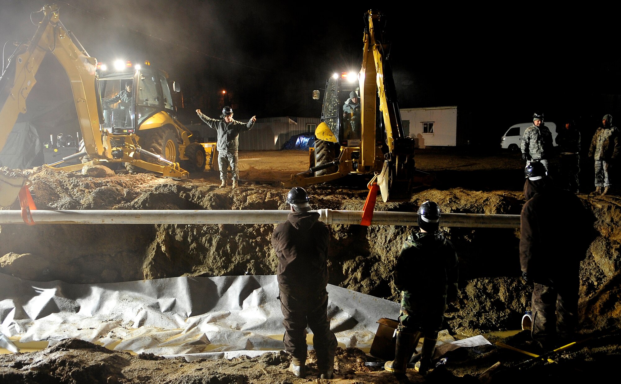 Airmen from the 51st Civil Engineer Squadron replace a section of an eight-inch water main that ruptured at Osan Air Base, Republic of Korea, Nov. 20. The pipe broke due to an underground slippage of concrete that was used to cover a pre-existing benjo ditch near the pipes. Airmen and civilians from agencies across Osan worked together for more than 24 hours to repair the broken eight and 12 inch water mains. (U.S. Air Force photo/Staff Sgt. Brian Ferguson)

