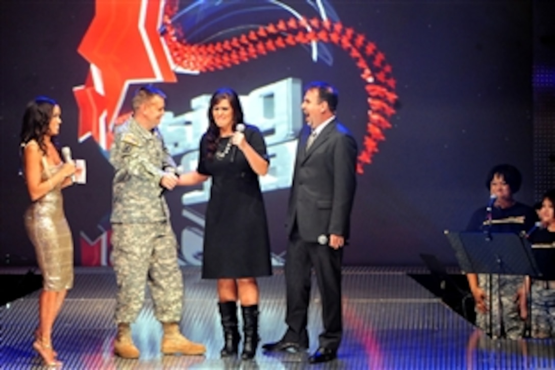 Co-host GeNienne Samuels, left, announces Army spouse Lisa Pratt of Fort Carson, Colo., as the winner of the 2009 Operation Rising Star singing contest at Wallace Theater on Fort Belvoir, Va., Nov. 20, 2009. Runner-up Capt. Donald Williamson, second from left, moves to give Pratt a congratulatory hug alongside co-host Victor Hurtado and members of the U.S. Army Band's Downrange. 
