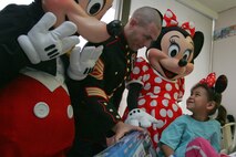 SECAUCUS, N.J. -- Gunnery Sgt. Tobin Eckstine, training chief, Golf Company, 2nd Battalion, 25th Marine Regiment, along with Mickey and Minnie Mouse present a toy to a girl in Meadowlands Hospital, Nov. 24. The event showed the partnership of the Walt Disney Corporation with the Marine Toys For Tots Program, which collects and distributes toys to children during the holiday season. The relationship between the Marines and Walt Disney goes back to 1948 when Walt created the original Toys for Tots logo. (Official Marine Corps photo by Sgt. Randall A. Clinton)