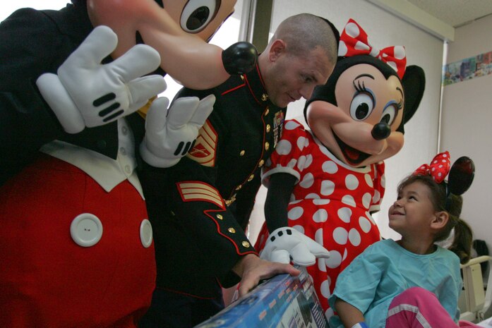 SECAUCUS, N.J. -- Gunnery Sgt. Tobin Eckstine, training chief, Golf Company, 2nd Battalion, 25th Marine Regiment, along with Mickey and Minnie Mouse present a toy to a girl in Meadowlands Hospital, Nov. 24. The event showed the partnership of the Walt Disney Corporation with the Marine Toys For Tots Program, which collects and distributes toys to children during the holiday season. The relationship between the Marines and Walt Disney goes back to 1948 when Walt created the original Toys for Tots logo. (Official Marine Corps photo by Sgt. Randall A. Clinton)