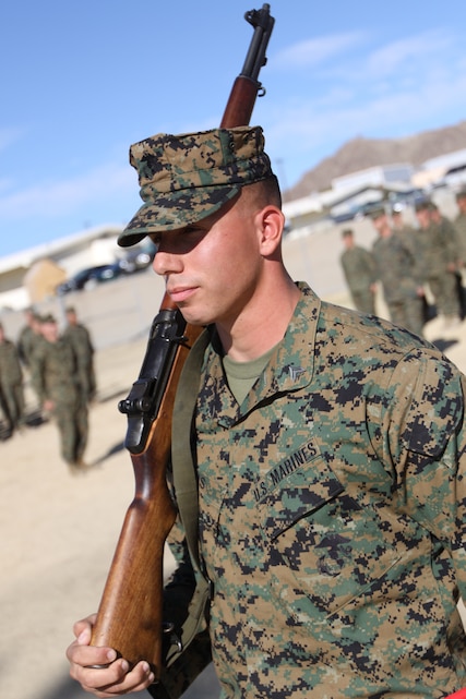 Cpl. Derrick Lewis, a squad leader with Company B, 1st Battalion, 7th Marine Regiment, takes his post after receiving an M1 Garand from Jim Gularte, a representative for the M1 for Vets program during a ceremony at Victory Field here Nov. 25. The program, which was originally established on the East Coast, now has roots in California and plans to give out more rifles to deserving veterans.