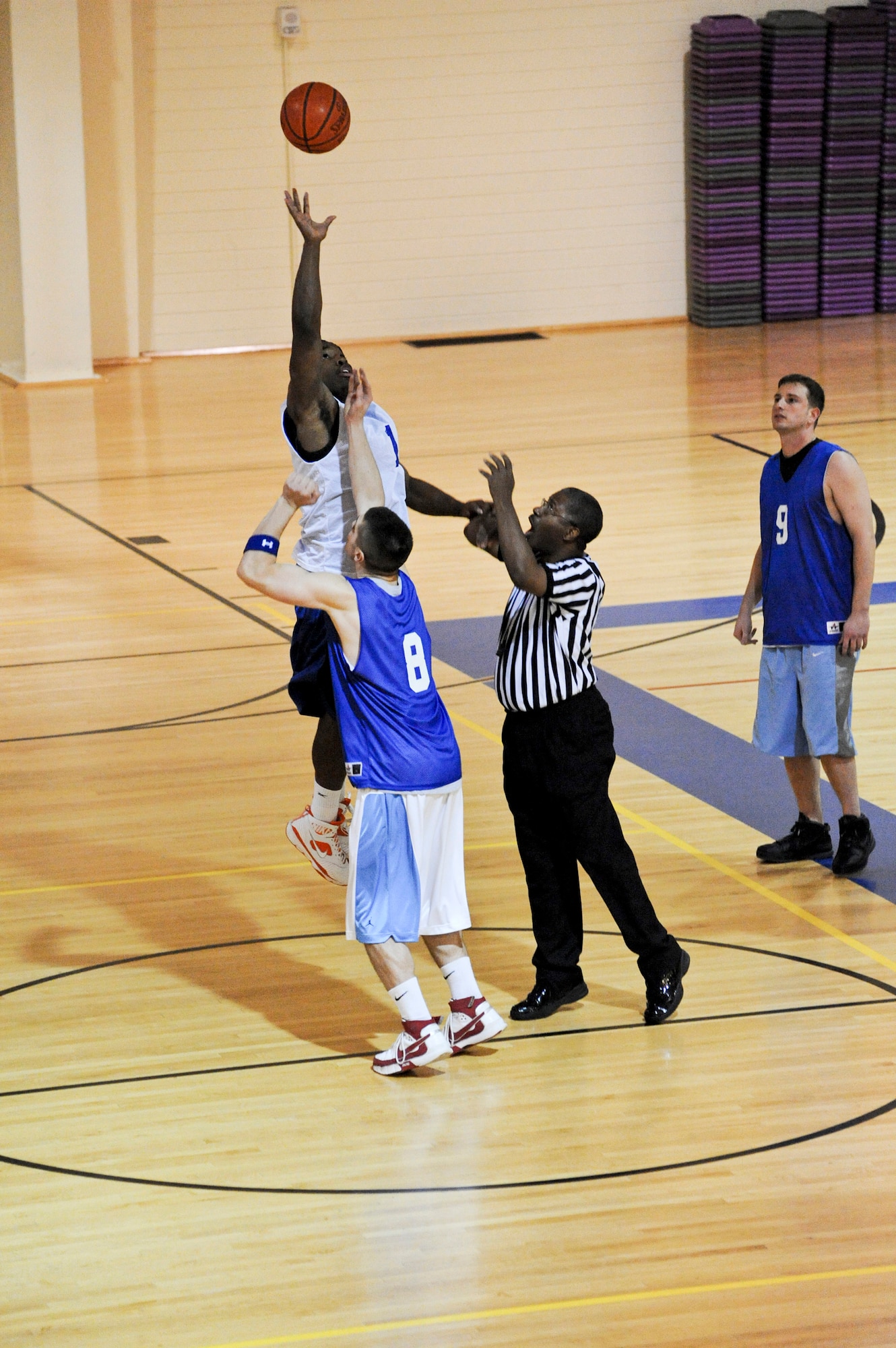 ELMENDORF AIR FORCE BASE, Alaska -- Members from the 3rd Communications Squadron, wearing white, and the 381st Intelligence Squadron, in blue, begin the game with a jump ball Nov. 24 at Elmendorf's Fitness Center. The 381st kept the game close in the beginning minutes, going back and forth, but could not recover from a 19 point deficit at half time. The 3rd CS came out on top with a final score 74-55. (U.S. Air Force photo/Airman 1st Class Christopher Gross)