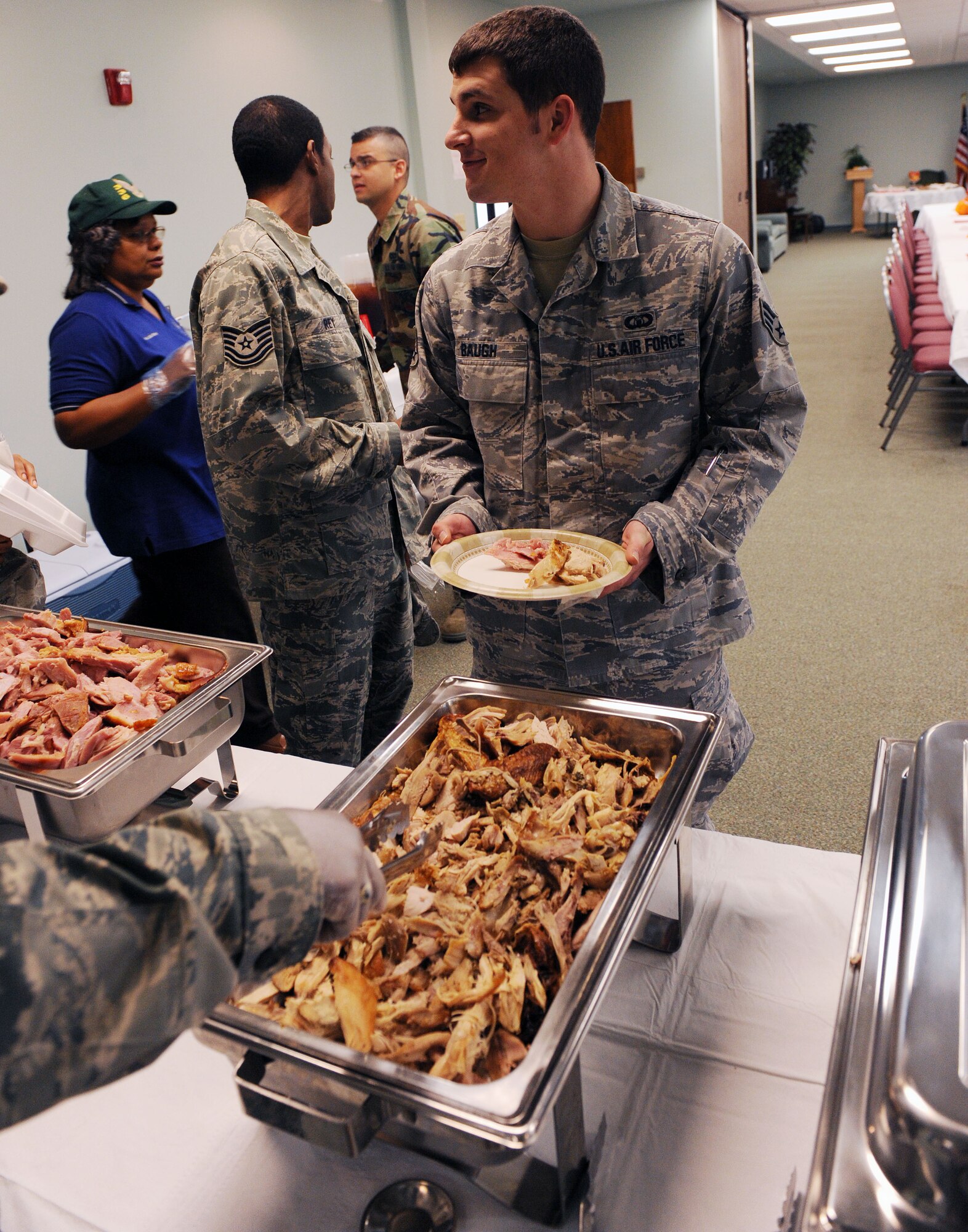 MOODY AIR FORCE BASE, Ga. -- Senior Airman Samuel Baugh, 23rd Operation Support Squadron air traffic controller, smiles and jokes with fellow Airmen while receiving a plate of food at the base chapel during the Airman Thanksgiving luncheon here Nov. 24. The luncheon was intended for single Airmen living on base who are away from home for the holiday. (U.S. Air Force photo by Airman 1st Class Joshua Green)
