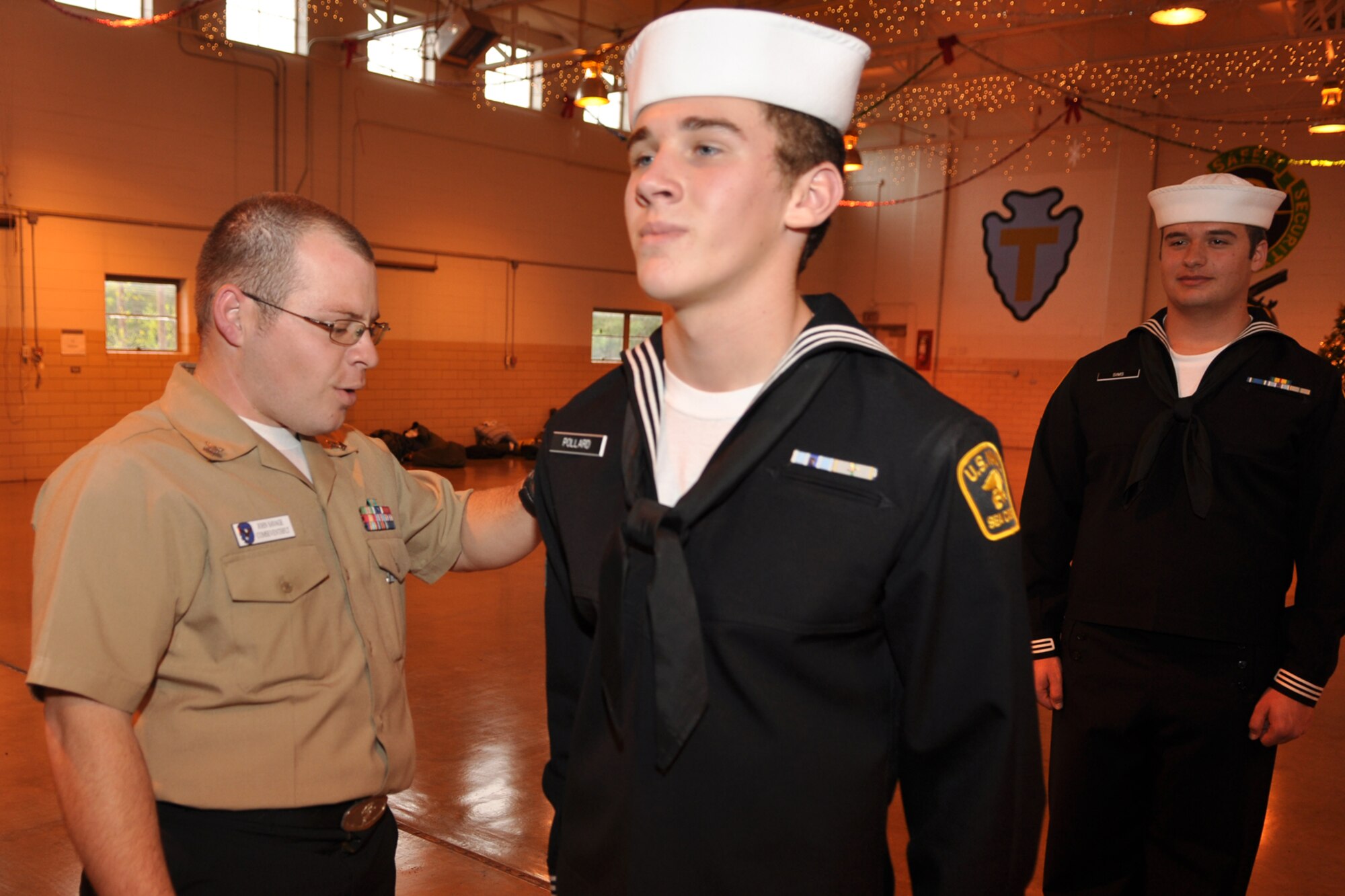U.S. Navy Petty Officer 2nd Class John Savage inspects the dress uniform of U.S. Naval Sea Cadet Corp cadet Harrison Pollard during the drill weekend for the Tyler Joint Force Battalion at the US Army National Guard Armory in Tyler, Texas, November 21, 2009. Petty Officer Savage is a Yeoman assigned to the Commander U.S. 7th Fleet, Naval Air Station, Joint Reserve Base, Fort Worth, Texas. The TJFB cadets are preparing for a U.S. Flag Retirement Ceremony at the American Legion Post 12 in Tyler. Early next year, the cadets plan to retire more than 100 flags that have been collected by various organizations and individuals. The ceremony is used to promote American Heritage and provide a Community service by honorably disposing of worn United States Flags. (Courtesy photo)