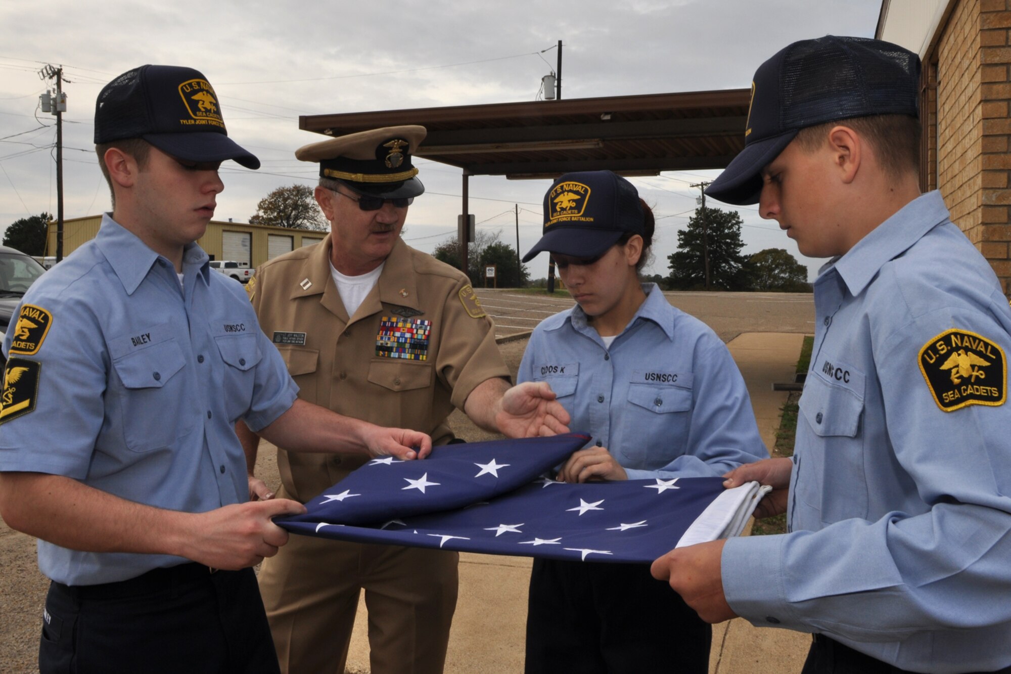 Lt. Jeff Walston, public affairs officer, U.S. Naval Sea Cadet Corps, Tyler Joint Force Battalion, assists in the training USNSCC Cadet Petty Officer 3rd Class Patrick Bailey, Recruit Katherine Cloos, and Cadet Joel Betts for a U.S. Flag Retirement Ceremony at the American Legion Post 12 in Tyler, Texas, November 21, 2009. Lieutenant Walston, also known as Technical Sgt. Walston is also a public affairs technician with the 917th Wing at Barksdale Air Force Base, La. Early next year, the TJFB cadets plan to retire more than 100 flags that have been collected by various organizations and individuals. The ceremony is used to promote American Heritage and provide a Community service by honorably disposing of worn United States Flags. (Courtesy photo)