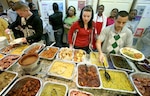 Staff Sgt. David Hernandez (right), 59th Medical Operations Group, helps Capt. Wendy Kosek get a plate of food Nov. 21 at the Fort Sam Houston Fisher House. More than 40 volunteers from Lackland's African American Cultural Association prepared a buffet for 300 people during their second annual Thanksgiving dinner at the Fisher House. Capt. Kosek is from Little Rock Air Force Base, Ark. (U.S. Air Force photo/Robbin Cresswell) 