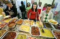 Staff Sgt. David Hernandez (right), 59th Medical Operations Group, helps Capt. Wendy Kosek get a plate of food Nov. 21 at the Fort Sam Houston Fisher House. More than 40 volunteers from Lackland's African American Cultural Association prepared a buffet for 300 people during their second annual Thanksgiving dinner at the Fisher House. Capt. Kosek is from Little Rock Air Force Base, Ark. (U.S. Air Force photo/Robbin Cresswell) 