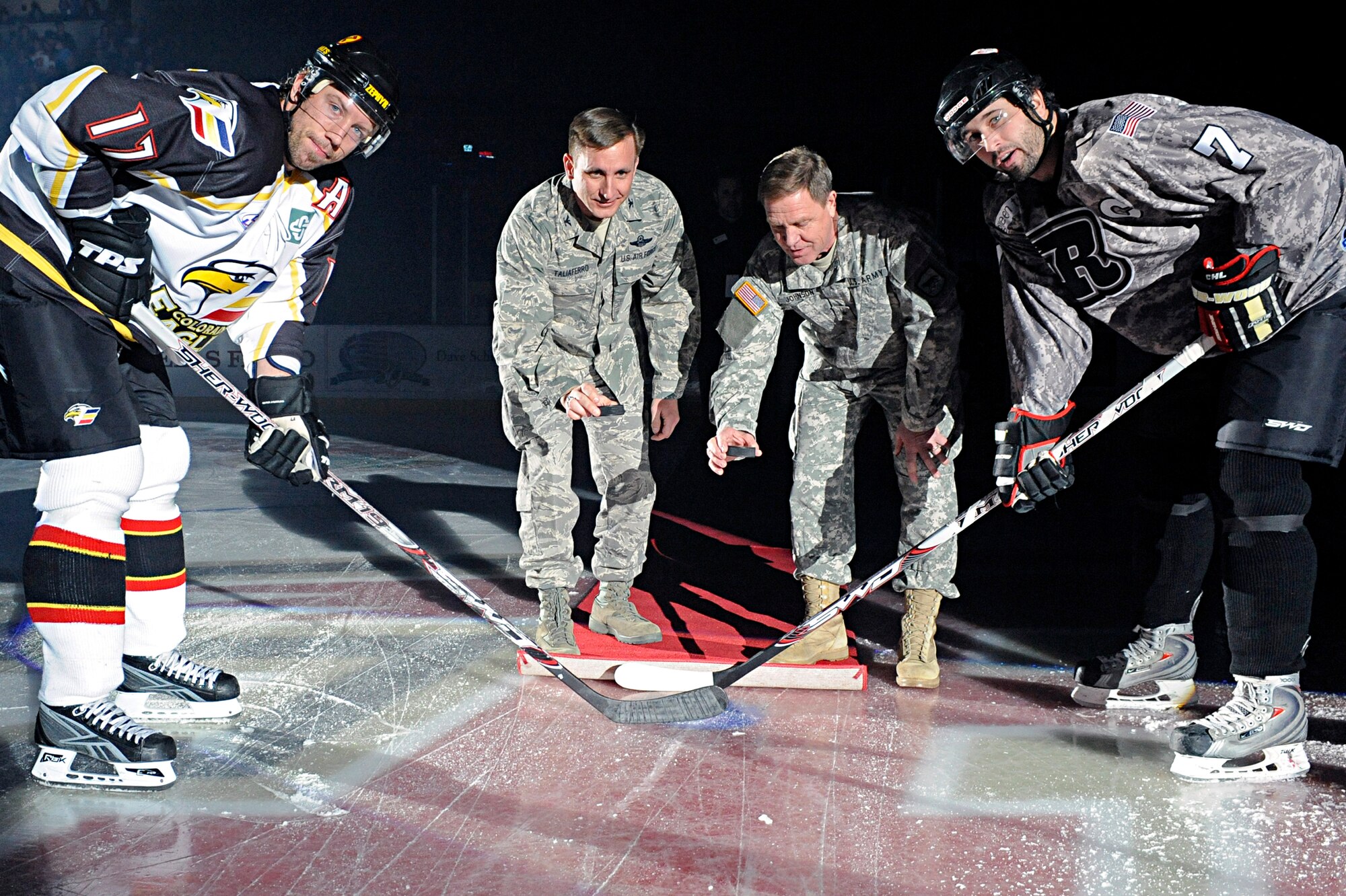 ELLSWORTH AIR FORCE BASE, S.D. -- (Center left) Col. Jeffrey Taliaferro, 28th Bomb Wing commander, and Brig. Gen. Theodore Johnson, South Dakota Army National Guard 196th Maneuver Enhancement Brigade commander, drop the ceremonial first pucks during a Military Appreciation Night hockey game Nov. 20. More than 5,000 fans attended the game between the Colorado Eagles and Rapid City Rush. (U.S. Air Force photo/Airman 1st Class Matthew Flynn)
