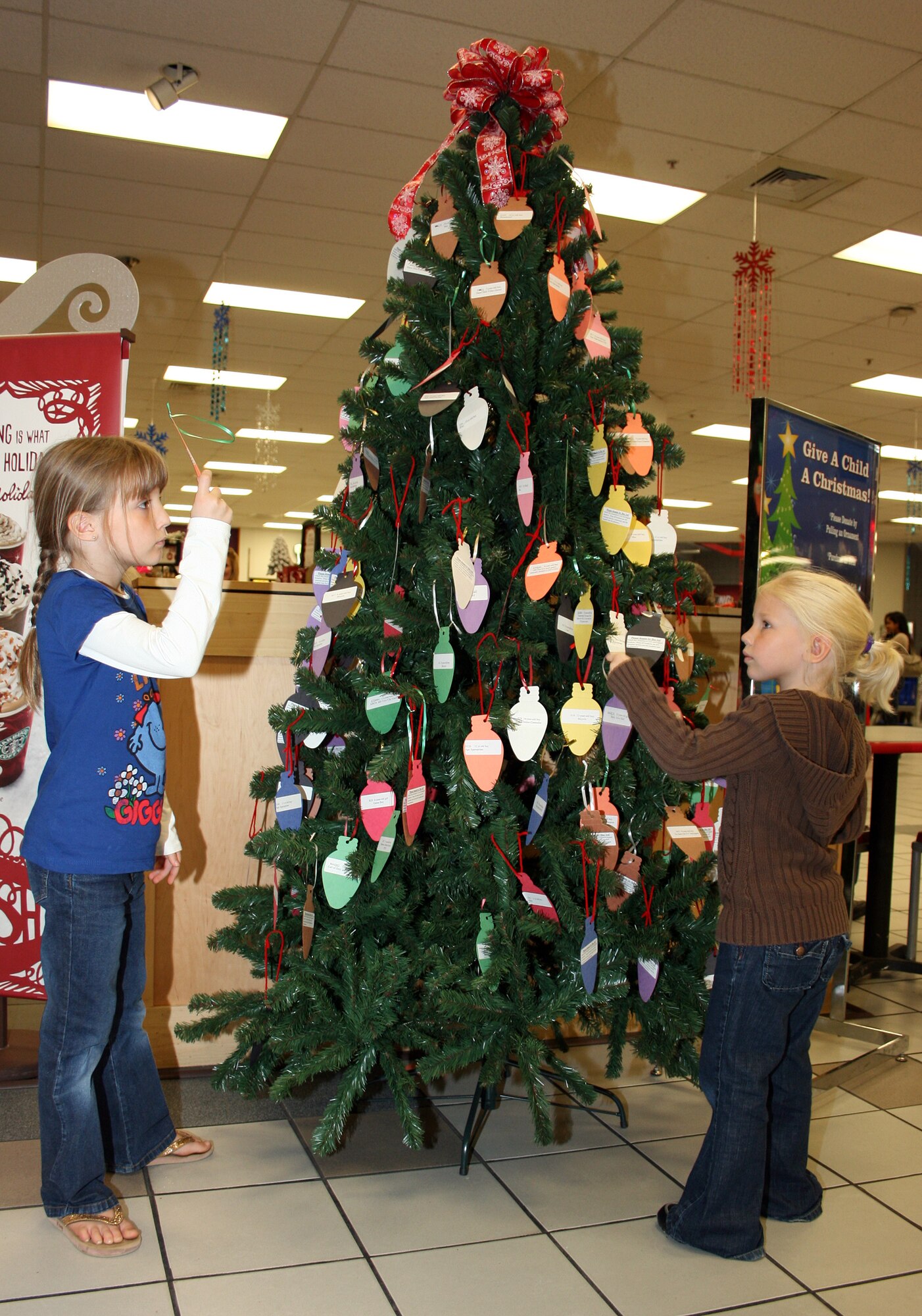 Aubree and Cecelia Voth talk about the gifts they will purchase for the Give a Child a Christmas program at Eglin's base exchange. The program, sponsored by the base Company Grade Officers' Council, provides gifts for local families in need of a little extra support over the holidays, many of whom belong to Team Eglin. To contribute to this program, stop by a giving tree prior to Dec. 4. Each ornament lists a desired present a specific child would like to receive. Pick an ornament, buy the item and turn in the unwrapped gift to the collection point at the BX or the hospital with the ornament attached. All gifts will be stored until "Santa" delivers them Dec. 5 during a Team Eglin event for the children here. (U.S. Air Force photo/2nd Lt. Andrew Caulk)
