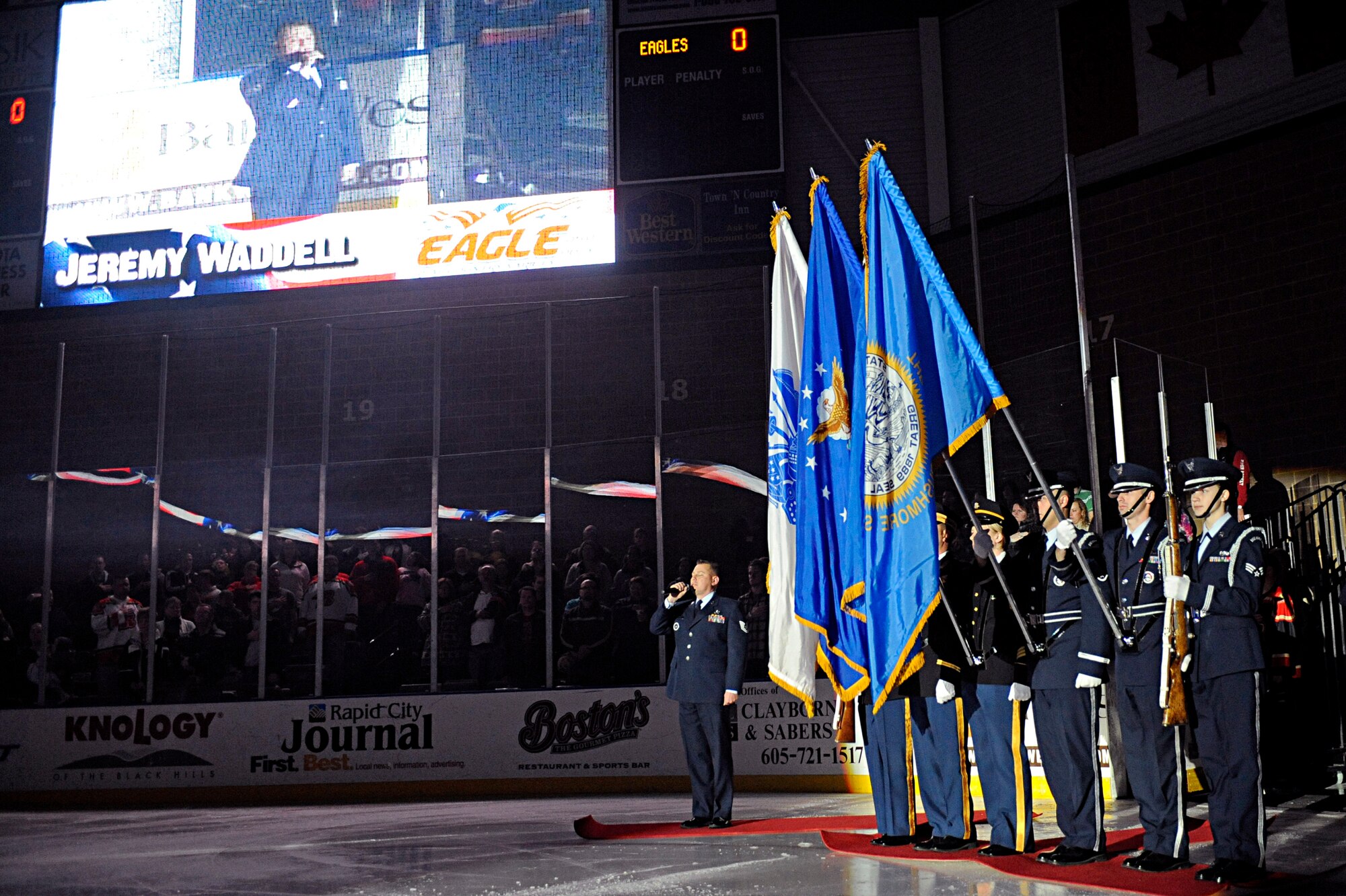 ELLSWORTH AIR FORCE BASE, S.D. -- (Left) Tech. Sgt. Jeremy Waddell, 372nd Training Squadron aerospace propulsion instructor, sings the National Anthem while the Ellsworth Honor Guard presents the colors at a Rapid City Rush game Nov. 20. The Rapid City Rush hosted a military appreciation night with more than 5,000 fans in attendance. (U.S. Air Force photo/Airman 1st Class Matthew Flynn)