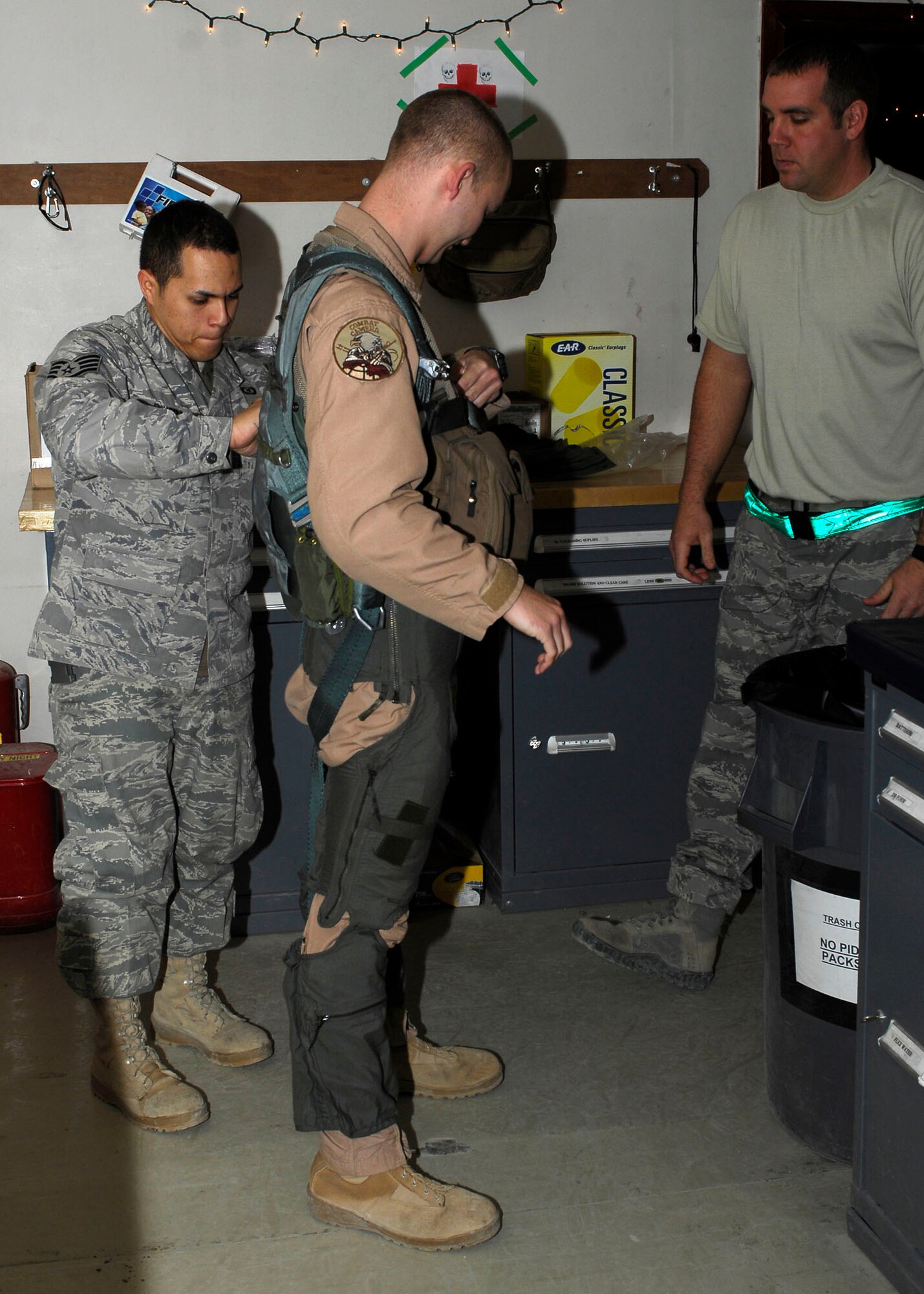 BAGRAM AIRFIELD, Afghanistan -- Staff Sgt. Michael Keller (right), a combat camera Airman, gets assistance with putting on a G-Suit properly from Staff Sgt. Jonathan Rivera (left), an aircrew flight equipment journeyman, Nov. 25, 2009.  A combat camera Airman is flying with the Fighters to visually tell their story.  A G-Suit is worn by aviators to avoid black-outs by putting pressure on the lower body to keep the blood circulating during high levels of accelerated force.  Sergeant Keller is deployed from Charleston Air Force Base, S.C., and hails from Clarkrange, Tenn.  Sergeant Rivera, a Puerto Rico native, is deployed from Seymour Johnson AFB N.C.  (U.S. Air Force photo/Senior Airman Felicia Juenke)