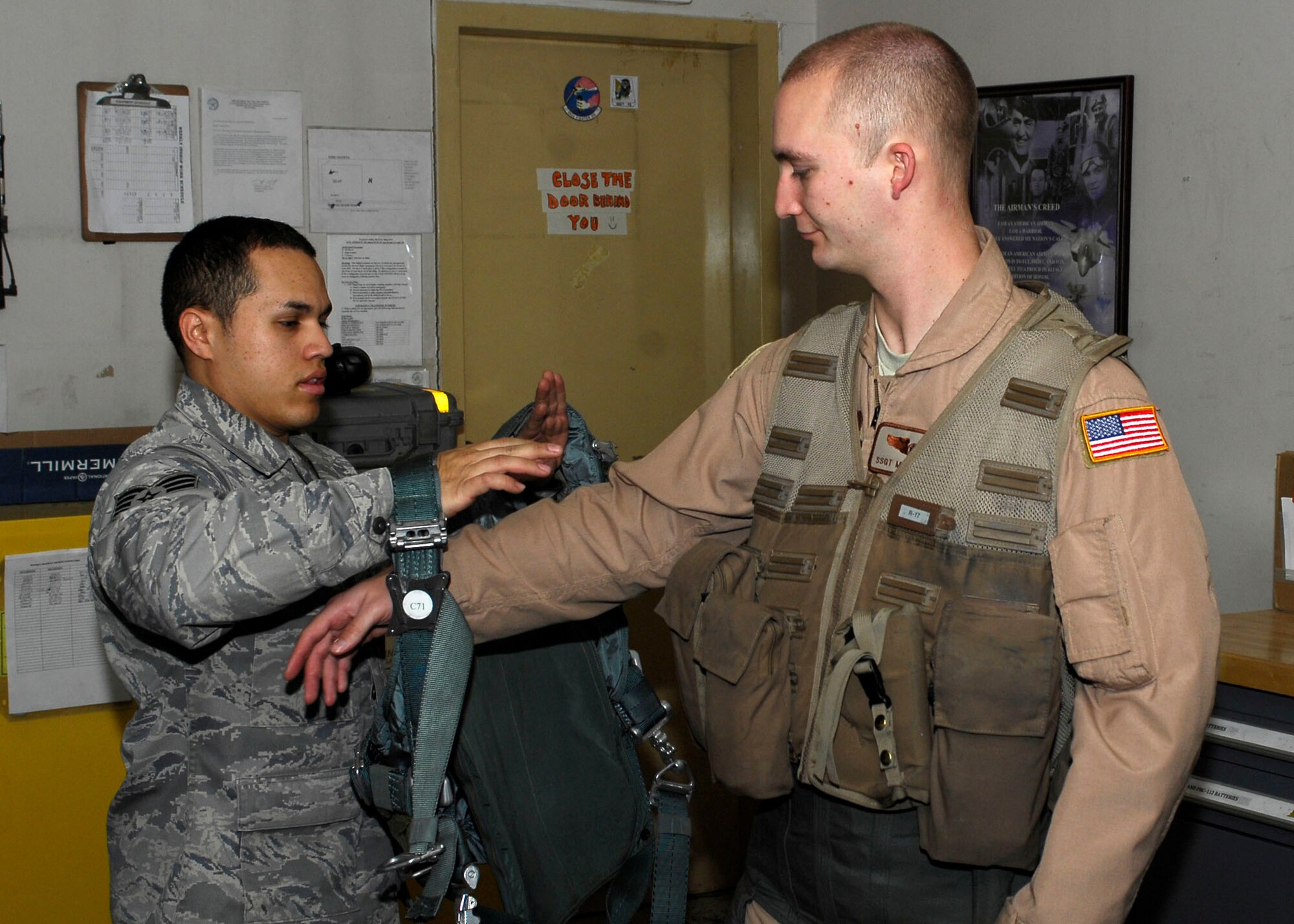 BAGRAM AIRFIELD, Afghanistan -- Staff Sgt. Michael Keller (right), a combat camera Airman, dons a survival vest from Staff Sgt. Jonathan Rivera (left), an aircrew flight equipment journeyman, Nov. 25, 2009.  A combat camera Airman is flying with the Fighters to visually tell their story.  Before going on a mission in an F-15E Strike Eagle, Sergeant Keller must be fitted or all the proper gear.  Sergeant Keller is deployed from Charleston Air Force Base, S.C., and hails from Clarkrange, Tenn.  Sergeant Rivera, a Puerto Rico native, is deployed from Seymour Johnson AFB N.C.  (U.S. Air Force photo/Senior Airman Felicia Juenke)