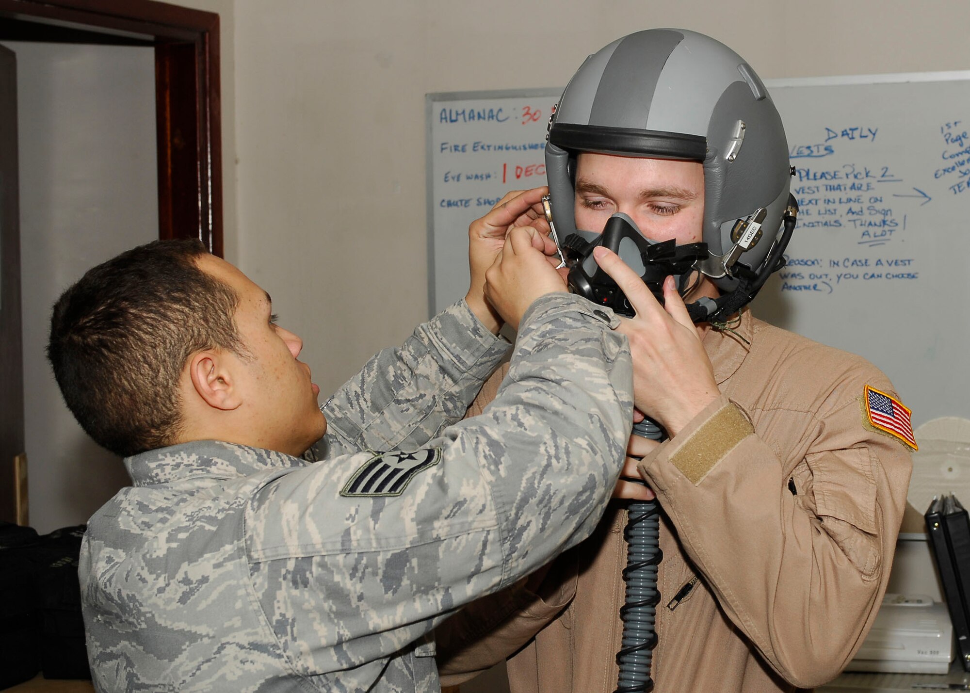 BAGRAM AIRFIELD, Afghanistan -- Staff Sgt. Michael Keller (right), a combat camera Airman, stabilizes a mask while Staff Sgt. Jonathan Rivera (left), an aircrew flight equipment journeyman, fits the mask and helmet to his face, Nov. 25, 2009.  A combat camera Airman is flying with the Fighters to visually tell their story.  Sergeant Keller is deployed from Charleston Air Force Base, S.C., and hails from Clarkrange, Tenn.  Sergeant Rivera, a Puerto Rico native, is deployed from Seymour Johnson, N.C.  (U.S. Air Force photo/Senior Airman Felicia Juenke)