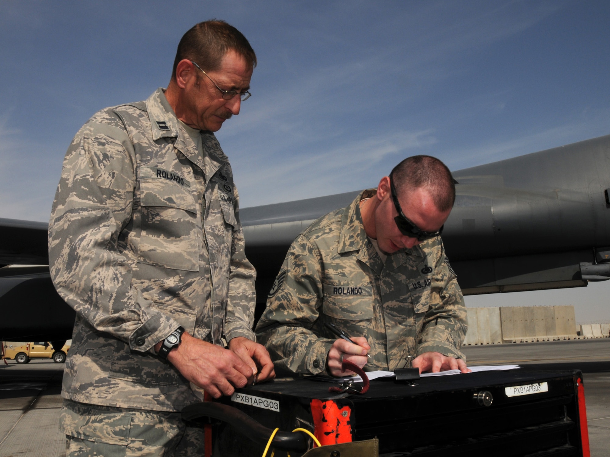 Captain Bruce Rolando, 332nd Expeditionary Security Forces Squadron, officiates the reenlistment of his son, Staff Sgt. Joshua Rolando, 455th Expeditionary Logistics Readiness Squadron, at a deployed location in Southwest Asia, Nov. 21, 2009. The father-son pair met up at the flightline of the 379th Air Expeditionary Wing from their respective deployments for the ceremony. Captain Rolando is deployed from Grand Forks Air Force Base, N.D. while Sergeant Rolando is deployed from RAF Lakenheath, England.(U.S. Air Force Photo/Tech. Sgt. Jason W. Edwards)