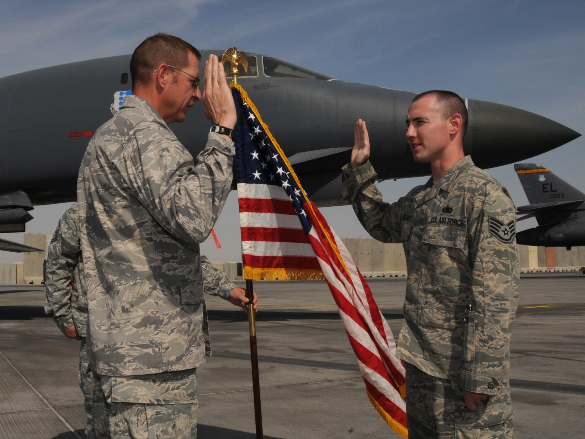 Captain Bruce Rolando, 332nd Expeditionary Security Forces Squadron, officiates the reenlistment of his son, Staff Sgt. Joshua Rolando, 455th Expeditionary Logistics Readiness Squadron, at a deployed location in Southwest Asia, Nov. 21, 2009. The father-son pair met up at the flightline of the 379th Air Expeditionary Wing from their respective deployments for the ceremony. Captain Rolando is deployed from Grand Forks Air Force Base, N.D. while Sergeant Rolando is deployed from RAF Lakenheath, England.(U.S. Air Force Photo/Tech. Sgt. Jason W. Edwards)