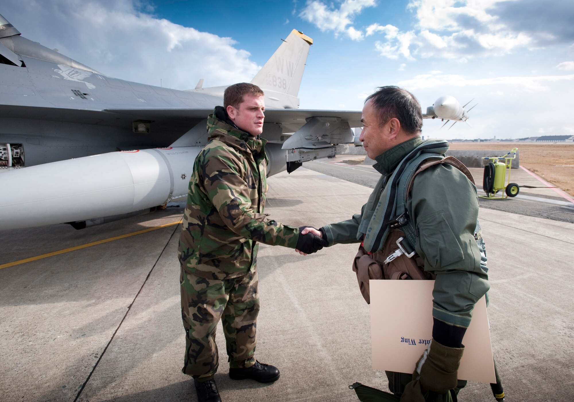 MISAWA AIR BASE, Japan -- Japan Air Self-Defense Force Lt. Gen. Kiyoshi Yada, Northern Air Defense Force commander, thanks Staff Sgt. Chad Miller, 14th Aircraft Maintenance Unit crewchief, for his assistance Nov. 20. Sergeant Miller made sure General Yada was secured in his seat and harness for his familiarization flight in one of the 35th Fighter Wing's F-16 Fighting Falcons. (U.S. Air Force photo/Staff Sgt. Samuel Morse)
