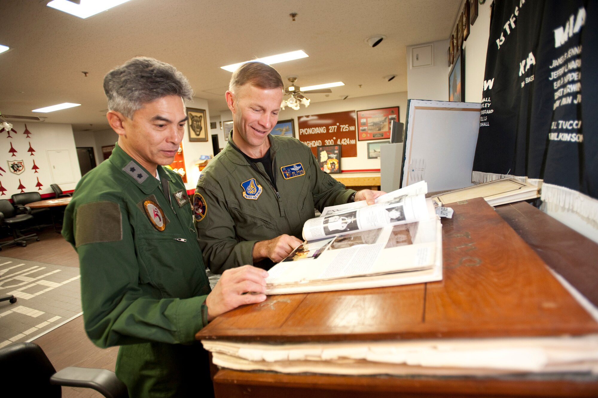 MISAWA AIR BASE, Japan -- Japan Air Self-Defense Force Maj. Gen. Hiroaki Maehara, 3rd Air Wing commander, and Col. RC Craig, 35th Fighter Wing vice commander, look through a photo album in the 13th Fighter Squadron heritage room Nov. 17. Colonel Craig gave a tour of the squadron prior to General Maehara's familiarization flight. (U.S. Air Force photo/Staff Sgt. Samuel Morse)