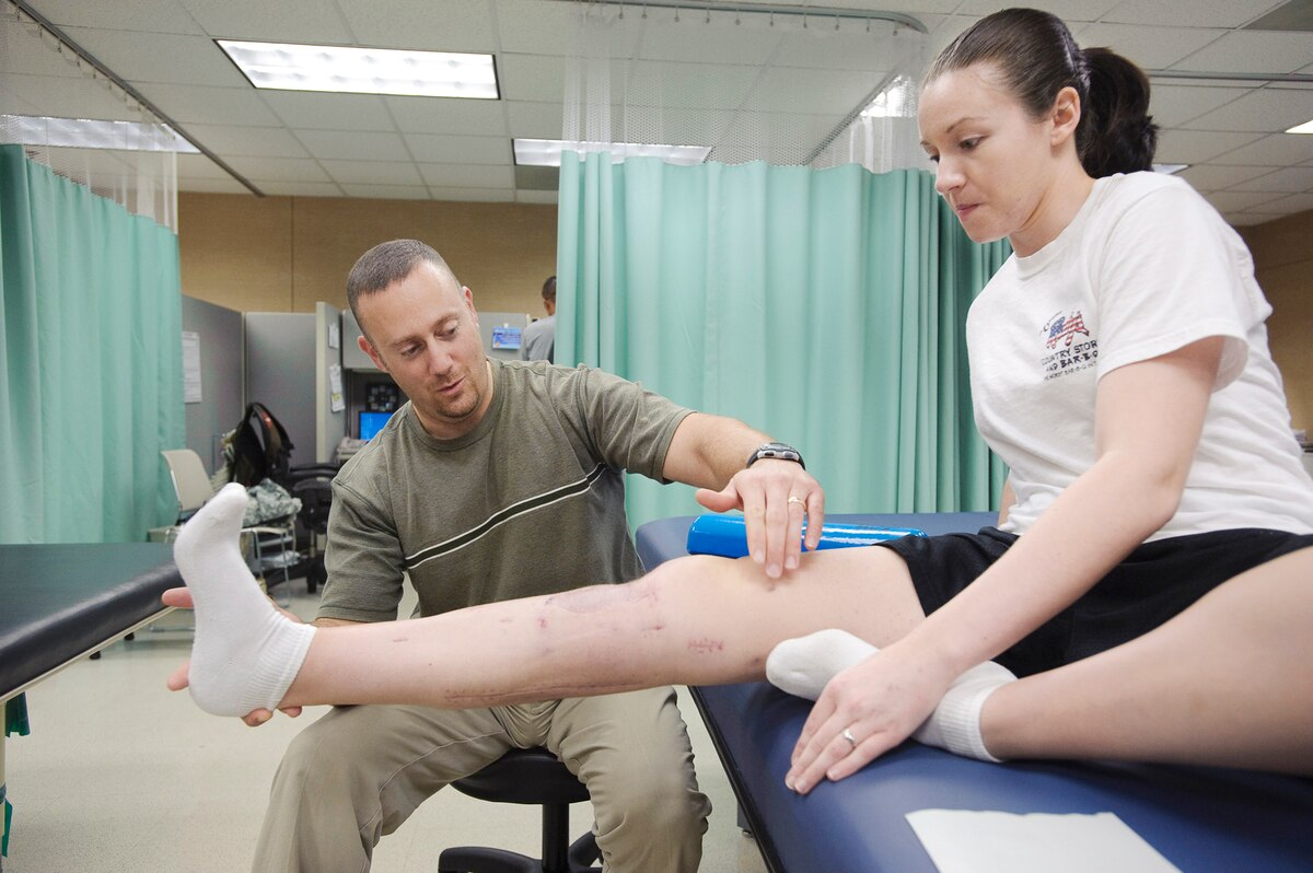 John Inzinna physical therapy assistant Brook Army Medical Center, San Antonio, TX,  helps Capt. Wendy Koseka 19th Airlift Wing legal officer Little Rock Air Force Base, build up her quadriceps muscle using gravity, during a physical therapy session at Brook Army Medical Center?s outpatient physical therapy clinic. (U.S. Air Force photo/Steve Thurow)