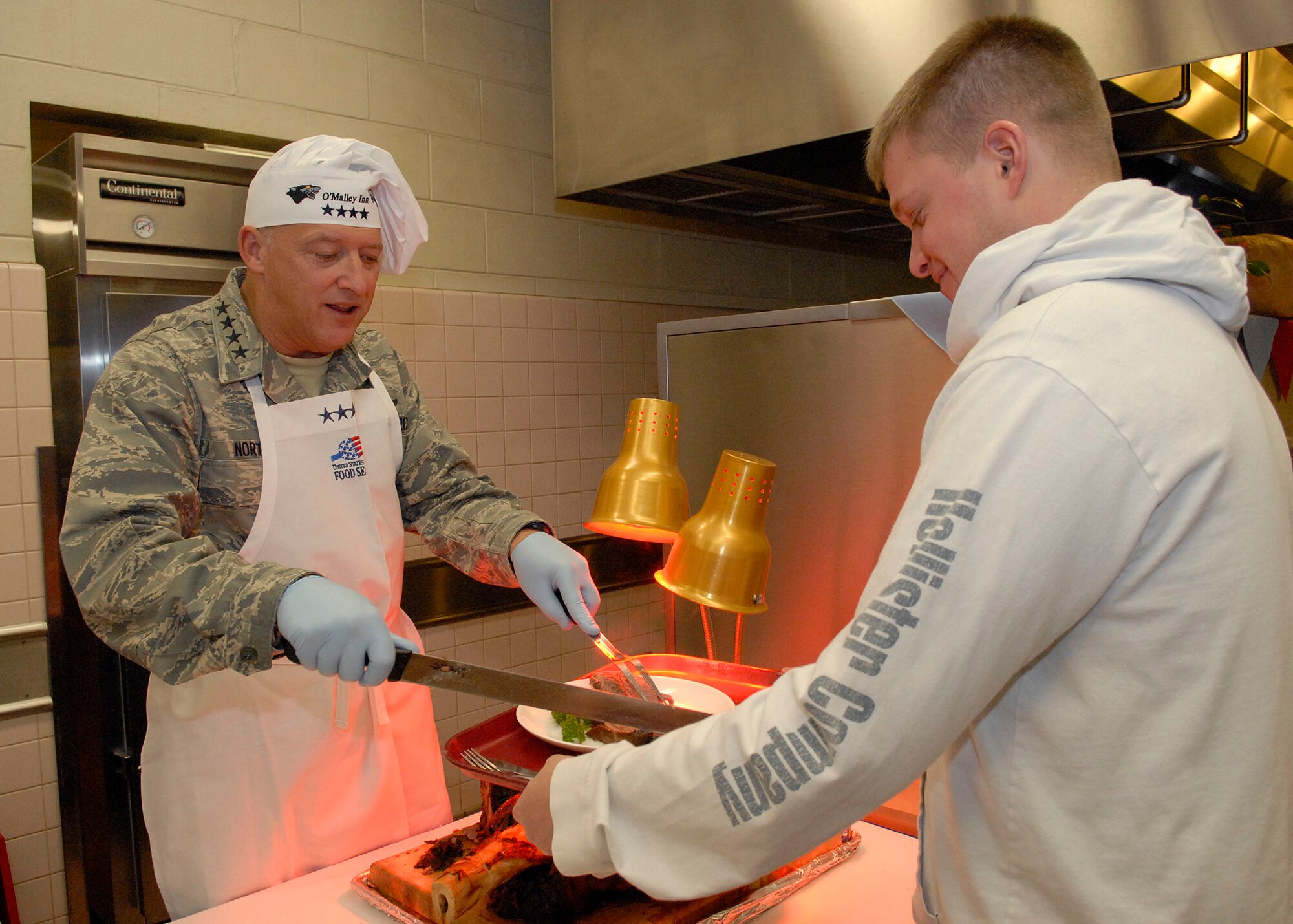 Gen. Gary North, Pacific Air Forces commander, cuts and serves roast to Staff Sgt. David Banks, 51st Medical Squadron, during Thanksgiving dinner Nov. 26 at Kunsan Air Base, Republic of Korea. General North, Chief Master Sgt. Brooke McLean, PACAF command chief, and four members of the Air Force Civilian Advisory Council toured Osan and Kunsan Air Bases, ROK, to celebrate Thanksgiving with the Airmen serving in the ROK. (U.S. Air Force photo/Tech. Sgt. Jerome Tayborn)