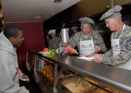 Gen. Gary North, Pacific Air Forces commander, and Chief Master Sgt. Brooke McLean, PACAF command chief, cut and serve roast to Airman 1st Class Peter Salas, 8th Communication Squadron, Nov. 26 at Osan Air Base, Republic of Korea.  General  North, Chief McLean, and four members of the Air Force Civilian Advisory Council visited Kunsan and Osan Air Bases, ROK, to celebrate Thanksgiving with the Airmen serving there. (U.S. Air Force photo/Tech. Sgt. Jerome Tayborn)
