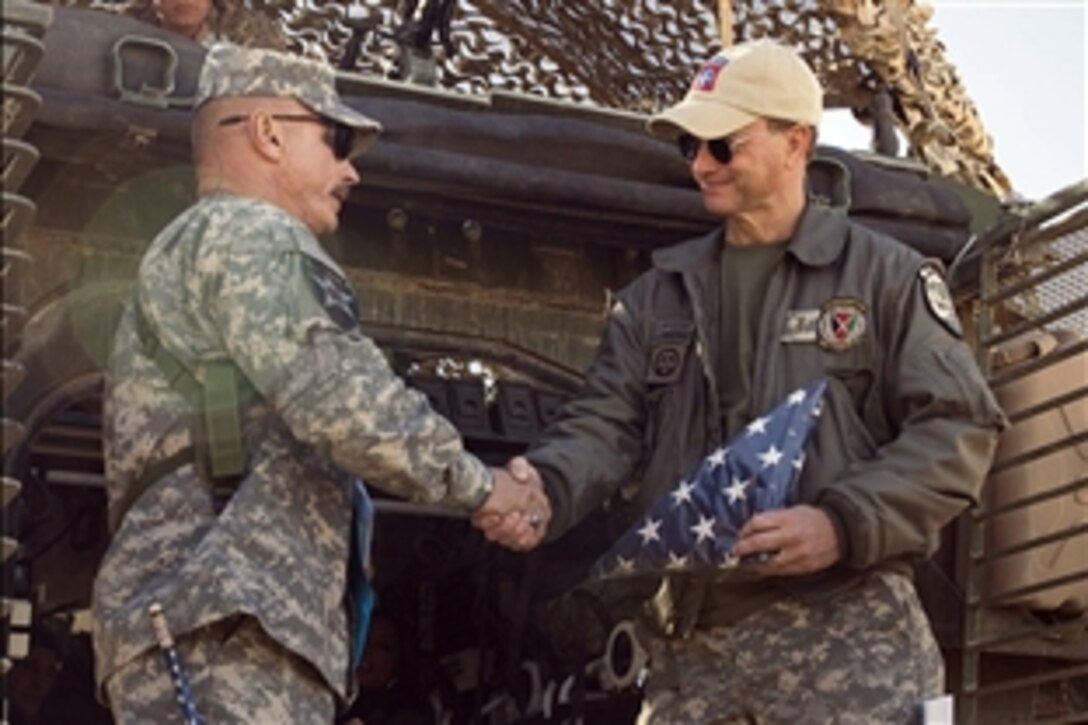 U.S. Army Sgt. Maj. Robert Prosser shakes actor Gary Sinise's hand after presenting him with the American flag and a special unit coin on Thanksgiving, Nov. 26, 2009. Sinise visited wounded soldiers in Kandahar, Afghanistan, after performing with his band, "The Lt. Dan Band." Prosser is assigned to the 5th Stryker Brigade Combat Team.